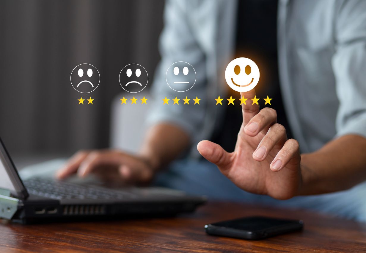 Person using a laptop and selecting a glowing happy face with five-star rating in a digital feedback interface.