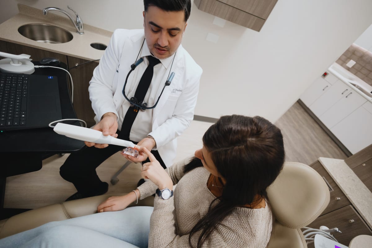 Dentist in white coat examining patient in clinical treatment room