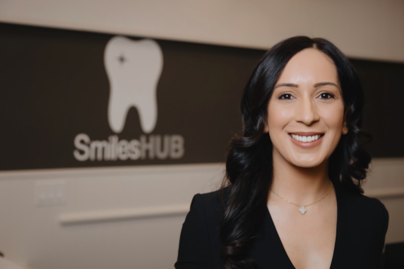Female dental professional smiling in front of SmilesHUB branded reception area
