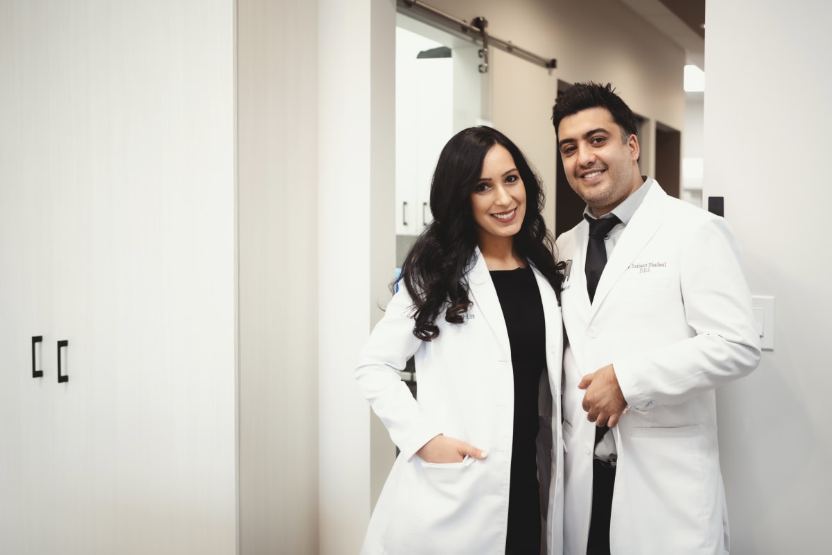 Female dentist in white coat consulting with male patient in treatment room
