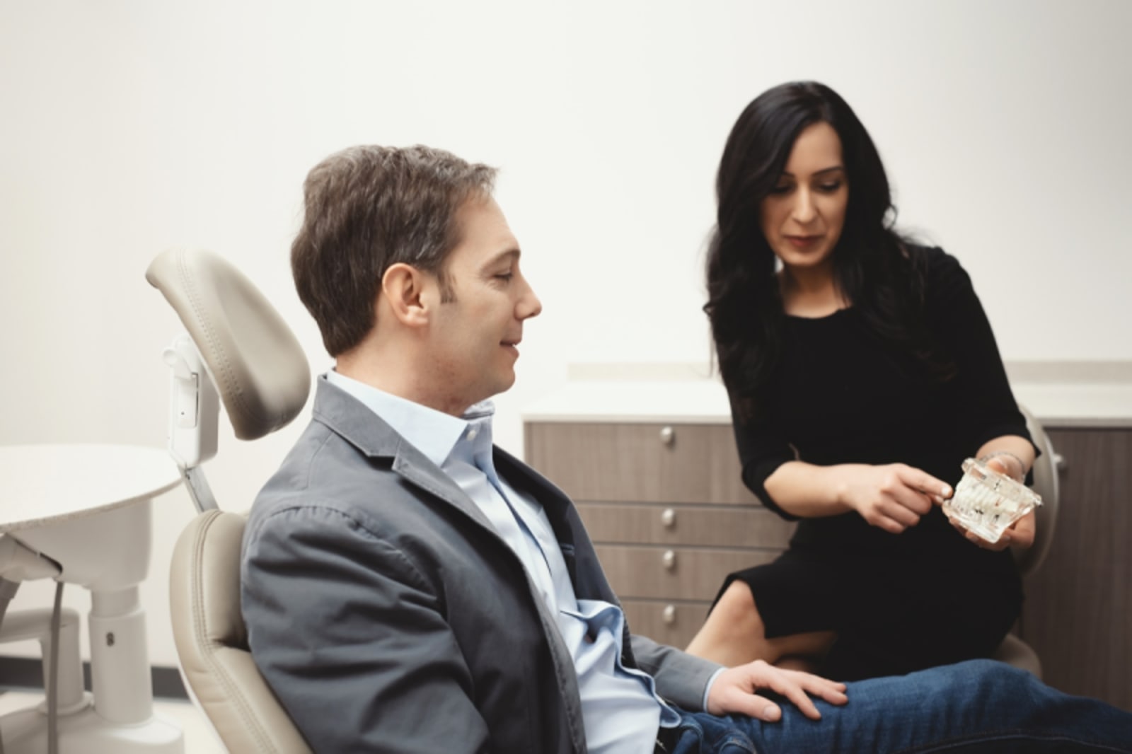 Female dentist discussing treatment plan with male patient in exam chair