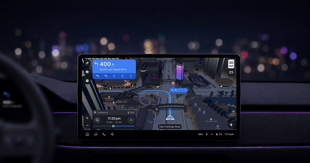 In-car night navigation screen with 3D buildings, blue route, and lane arrows painted on the road for an upcoming left turn.