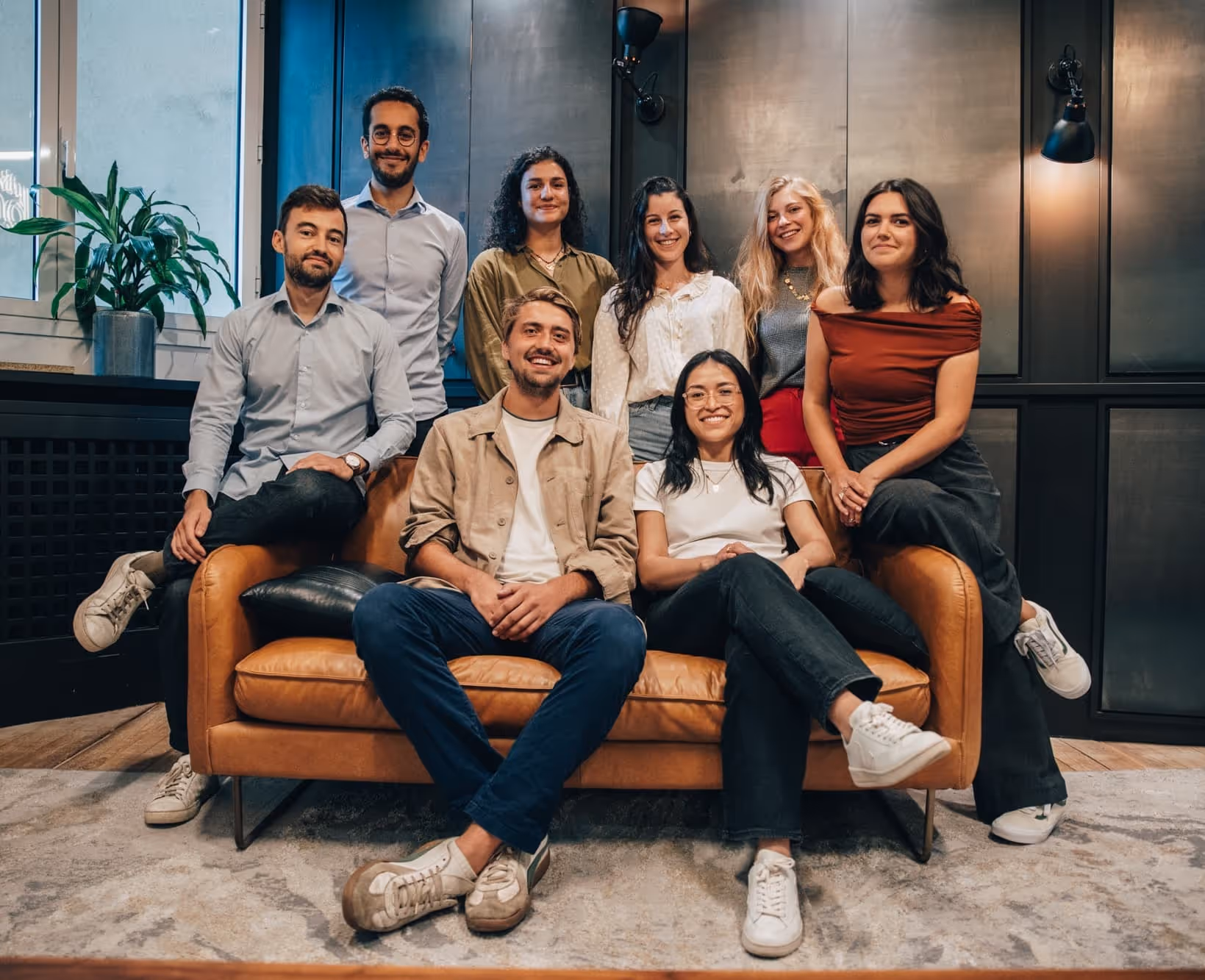 Groupe diversifié de collègues souriants assis sur un canapé en cuir