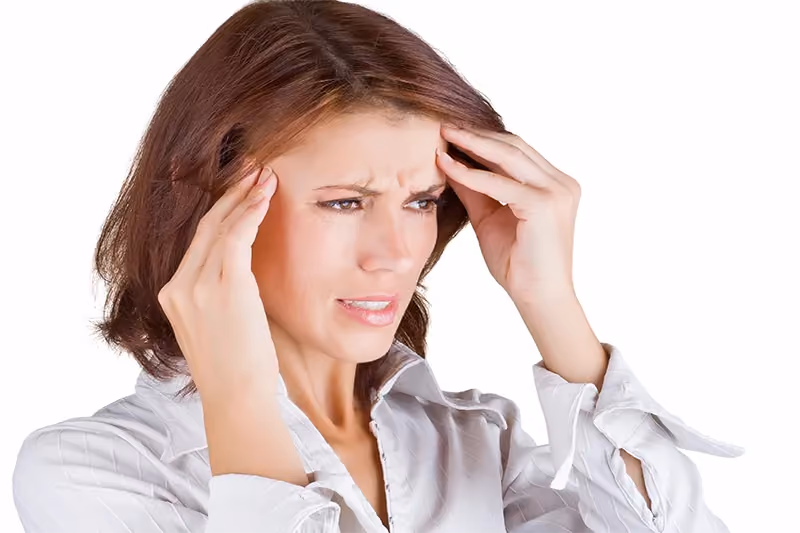 Woman in a white blouse holding her head, white background.