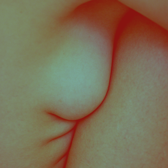 Naked woman pressing her breasts against her legs. 