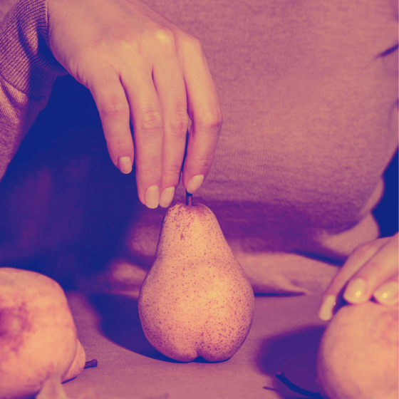 A woman holding the stem of a pear.