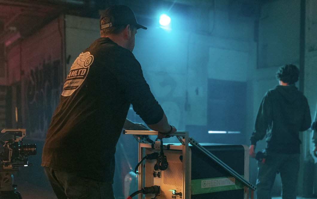 Man on film set pushing power station on cart