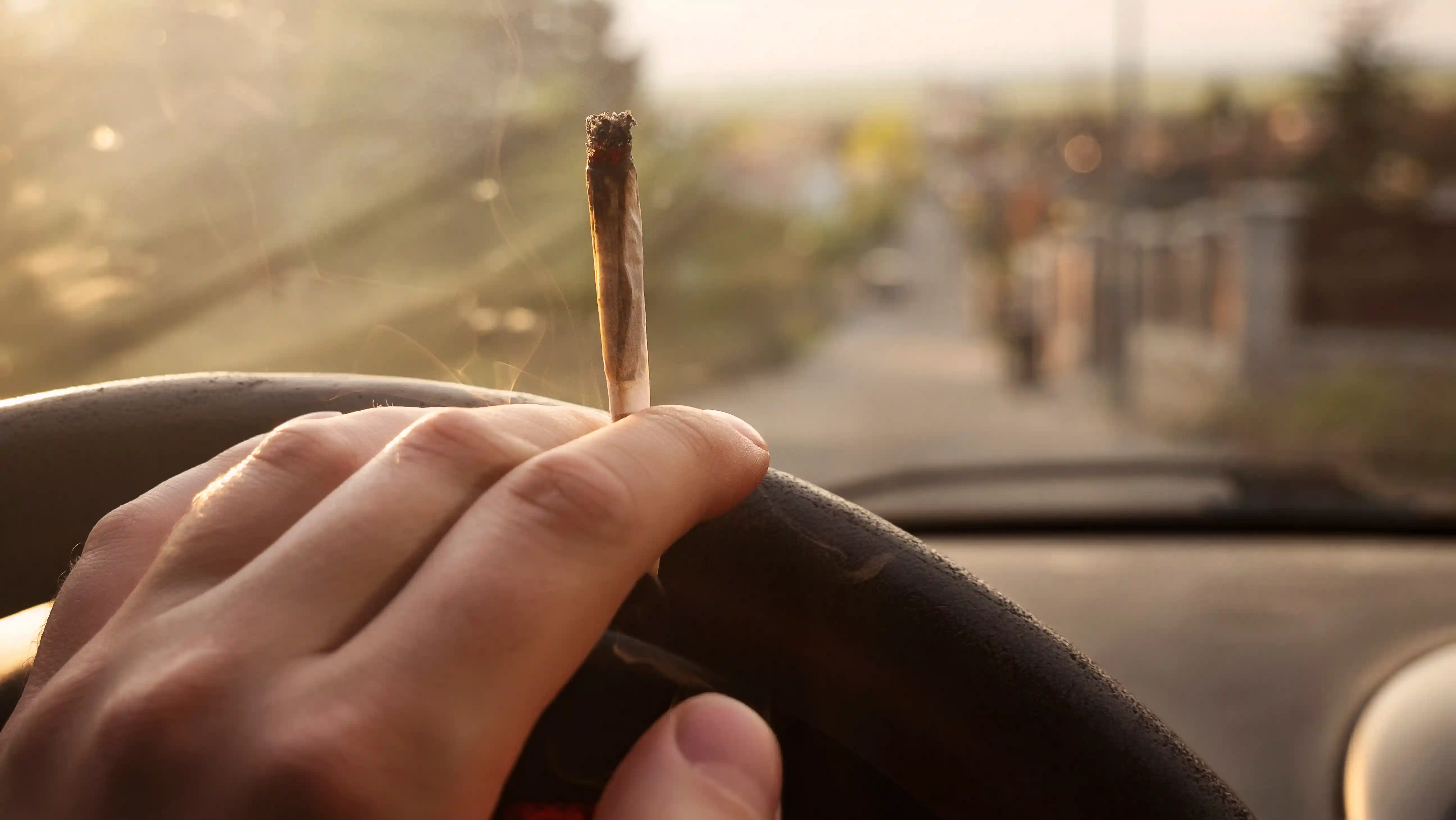 Person hält Joint während des Autofahrens 