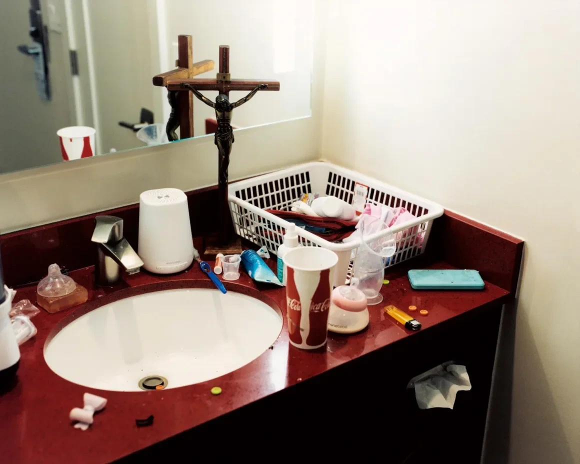 New Genesis by Abdulhamid Kircher — bathroom counter with crucifix, breast pump basket and feeding bottles photographed in a Los Angeles apartment.