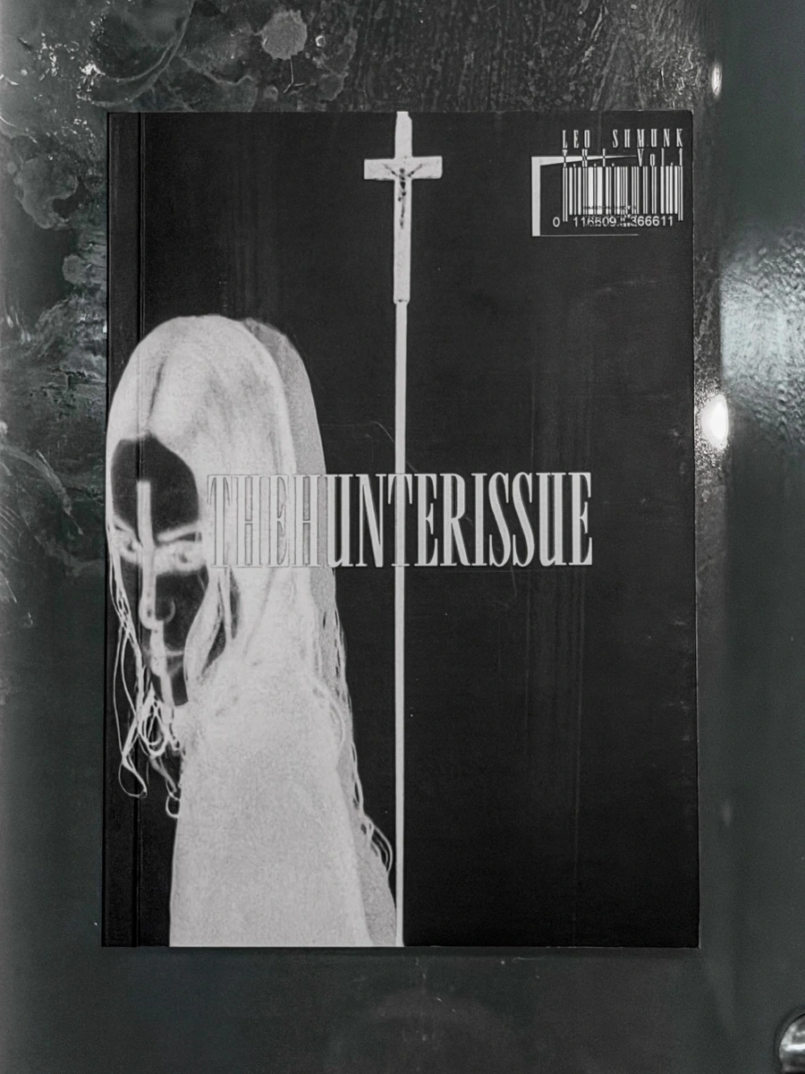 TheHunterIssue Vol.1 by Leo Shmunk, art book cover portrait crop, veiled figure with barcode, 2026