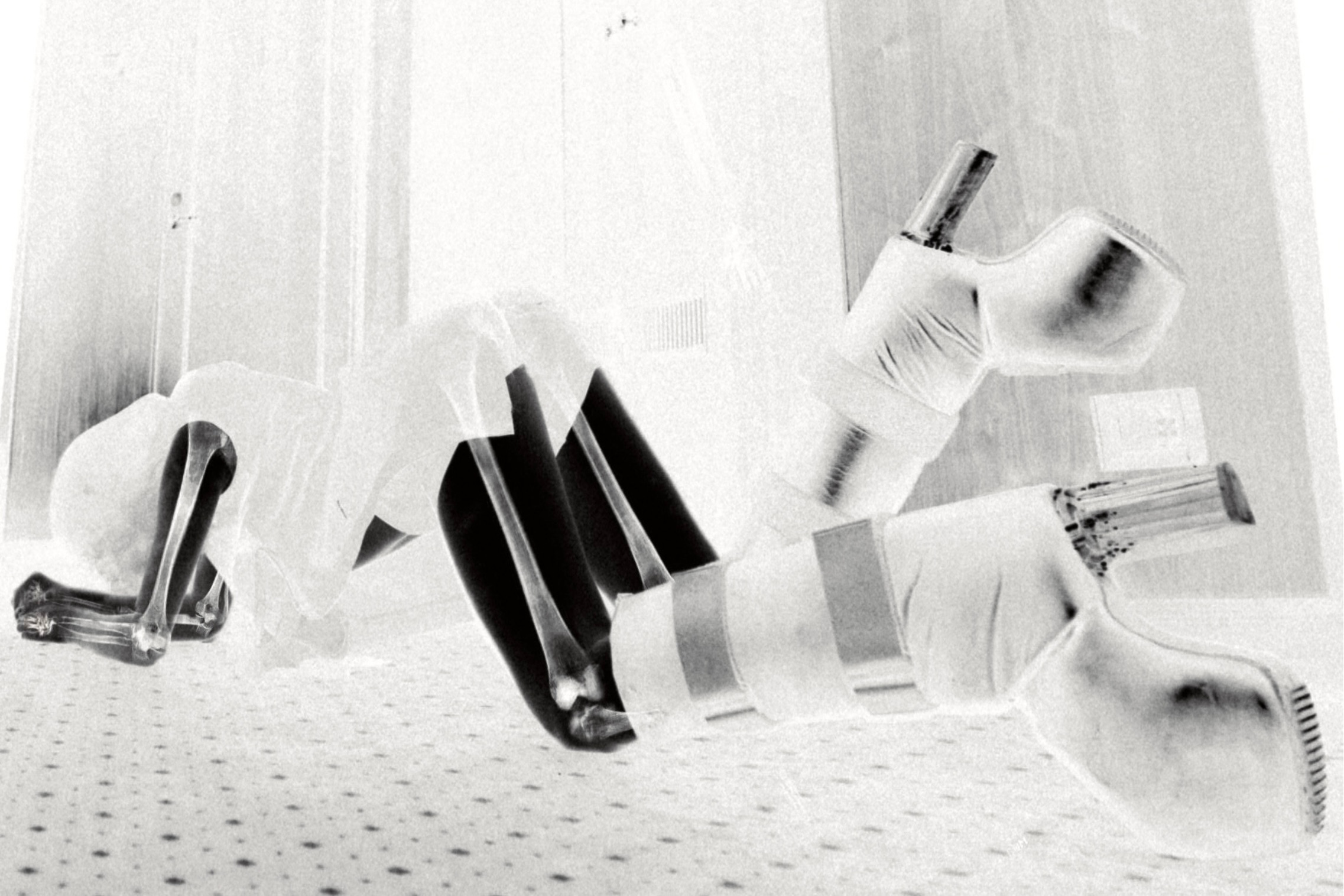 Spread from TheHunterIssue Vol.1 by Leo Shmunk, negative-image still of black stiletto pumps strapped and bandaged with white gauze on a dotted carpet, hardware blurred to a ghost trace, 2026. Photo: Leo Shmunk.