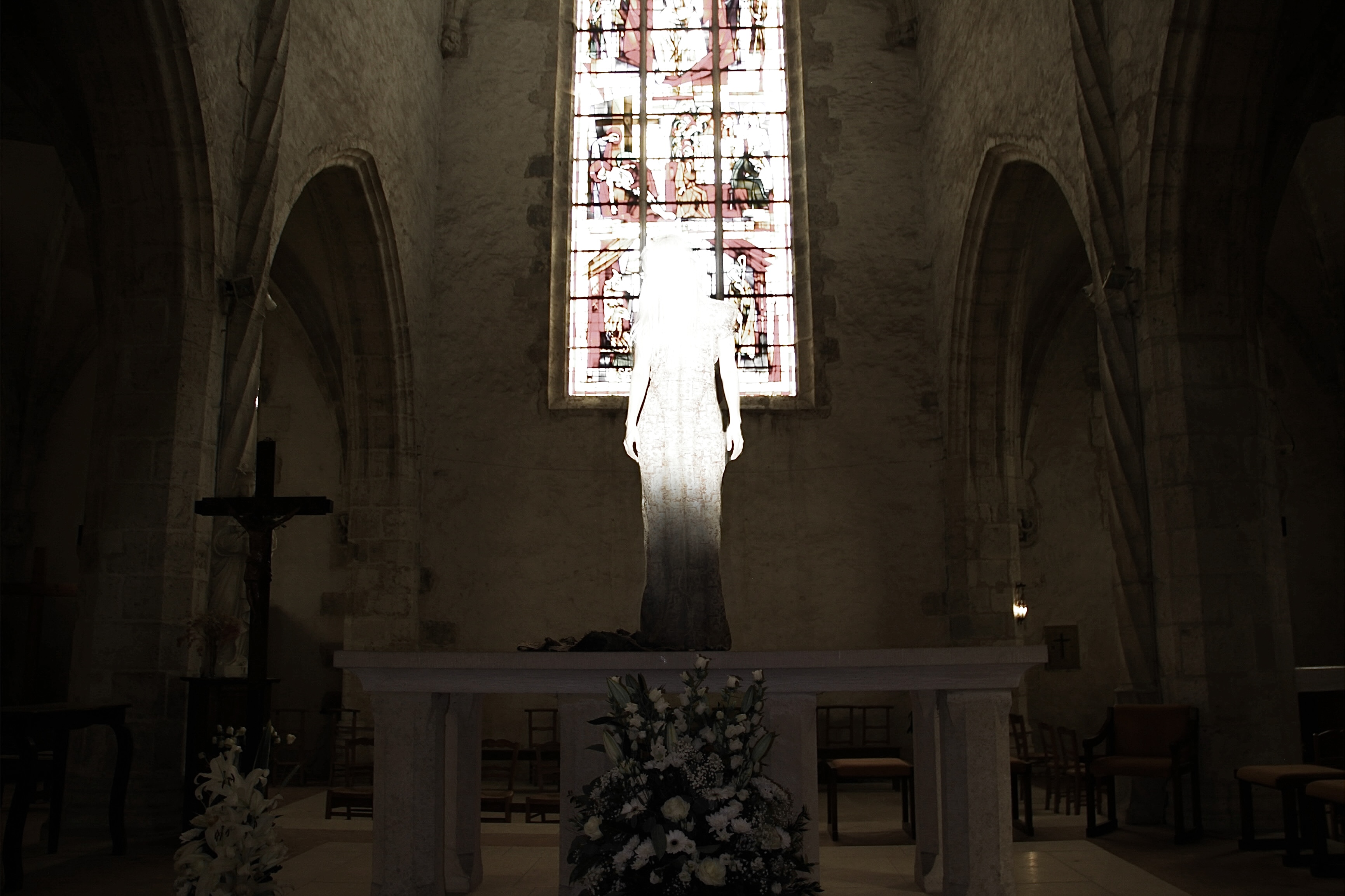 Spread from TheHunterIssue Vol.1 by Leo Shmunk, white-veiled figure standing on a stone church altar before a stained-glass window, wooden crucifix and floral arrangement flanking the nave, 2026. Photo: Leo Shmunk.