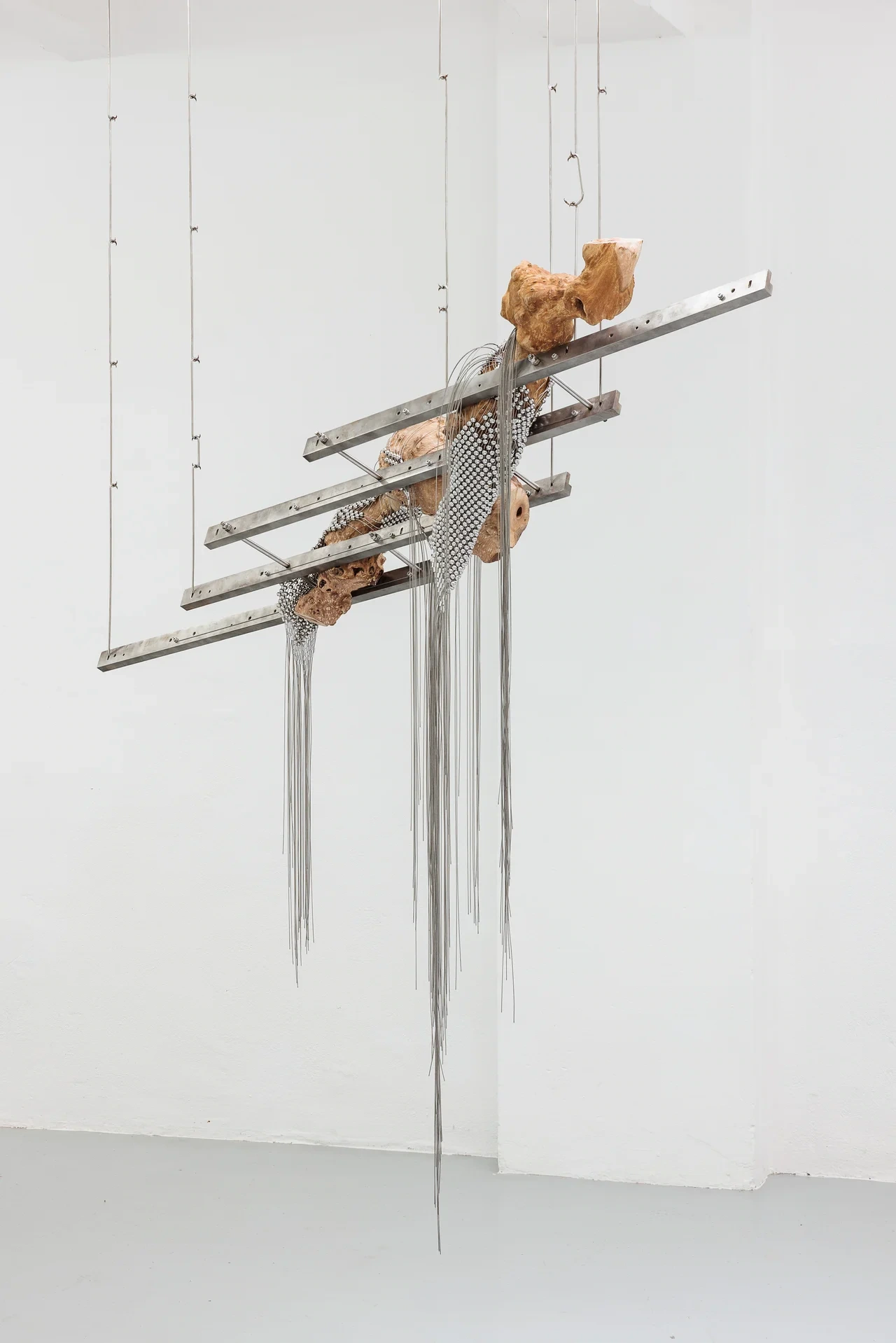 Zishi Han's xoxo series suspended on steel armatures at Gianni Manhattan, Vienna, London Plane wood sheathed in a handwoven steel-wire net.