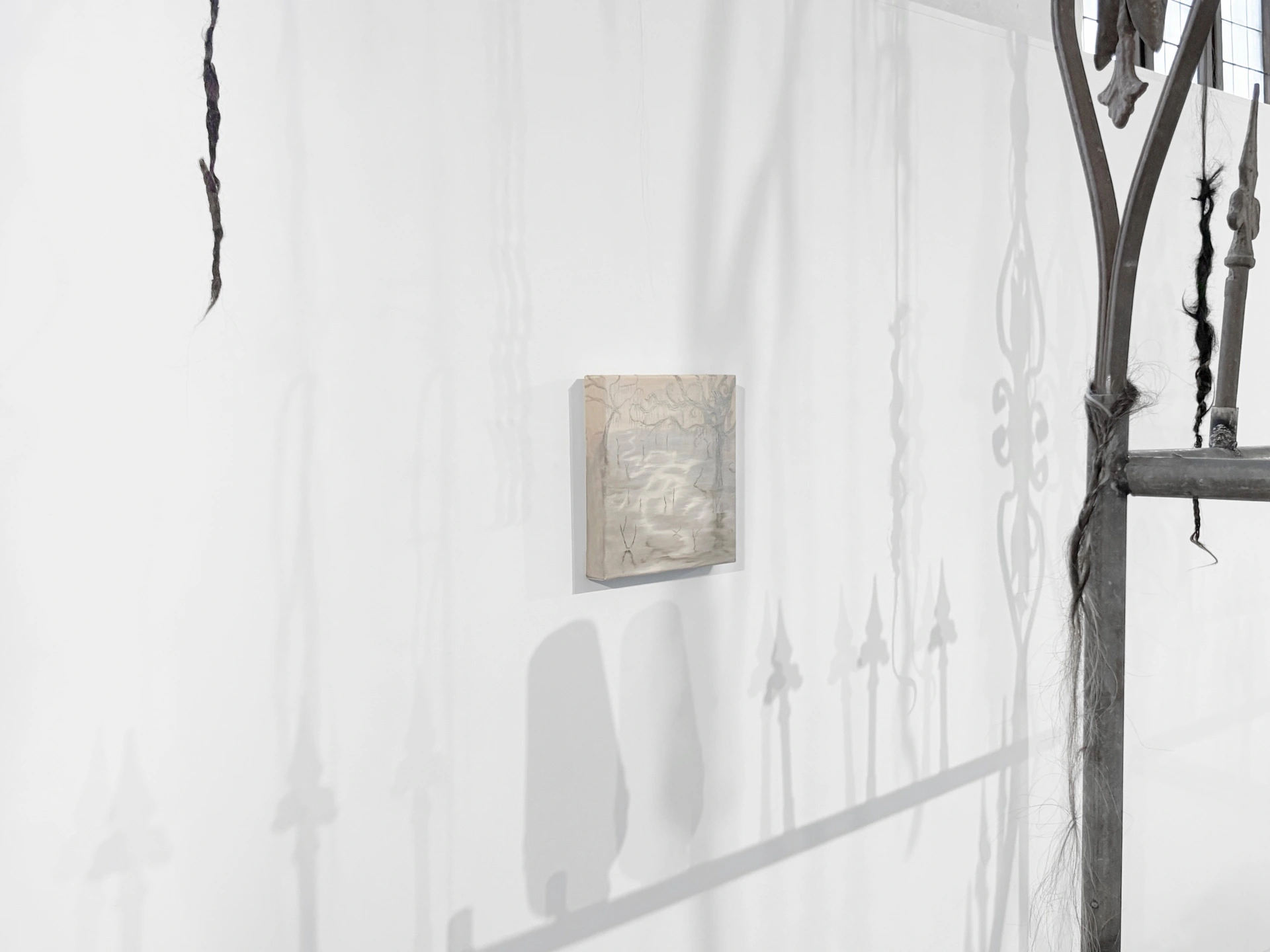 Angelika Puff, Swamp, a small misty canvas of a flooded landscape hung on a pale wall crossed by the cast shadows of the Bird Cage iron finials and hanging hair.
