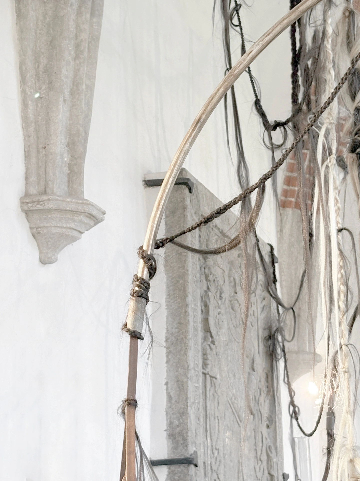 Angelika Puff, Bird Cage, 2025 — Bird Cage viewed from below, braided hair hanging from metal bars overhead against vaulted brick ceiling.