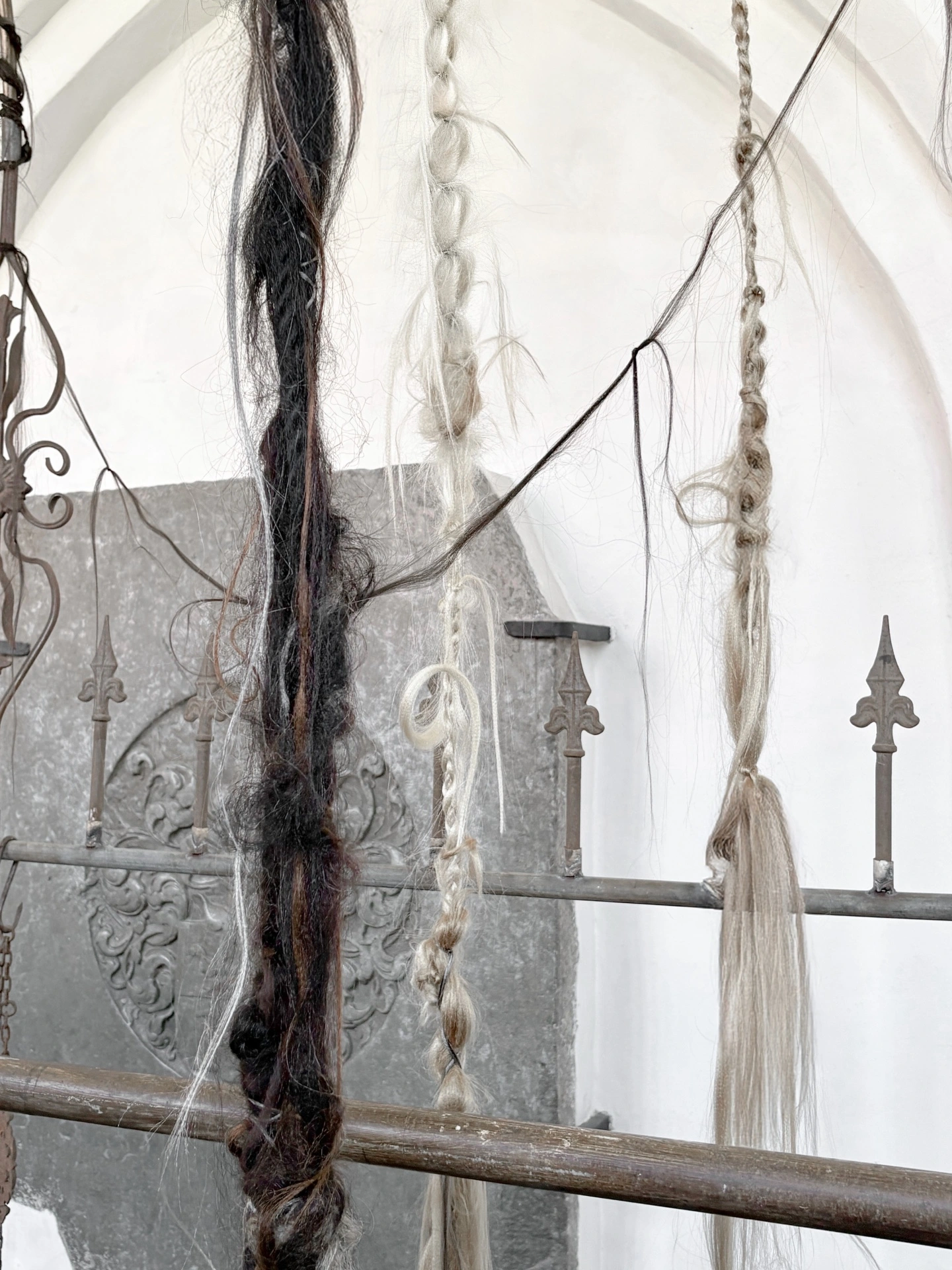 Angelika Puff, Bird Cage, 2025 — loose and matted dark hair strands draped over curved metal bars, cobwebbed light through Gothic windows.