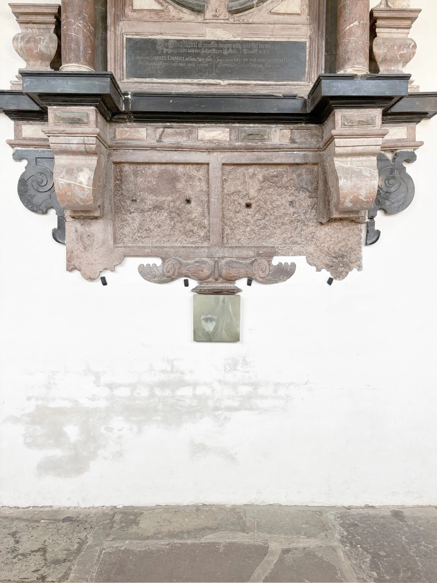 Angelika Puff, Chalice, a tiny green-toned canvas of a single suspended form mounted low on a white wall beneath the carved base of a Baroque stone epitaph.