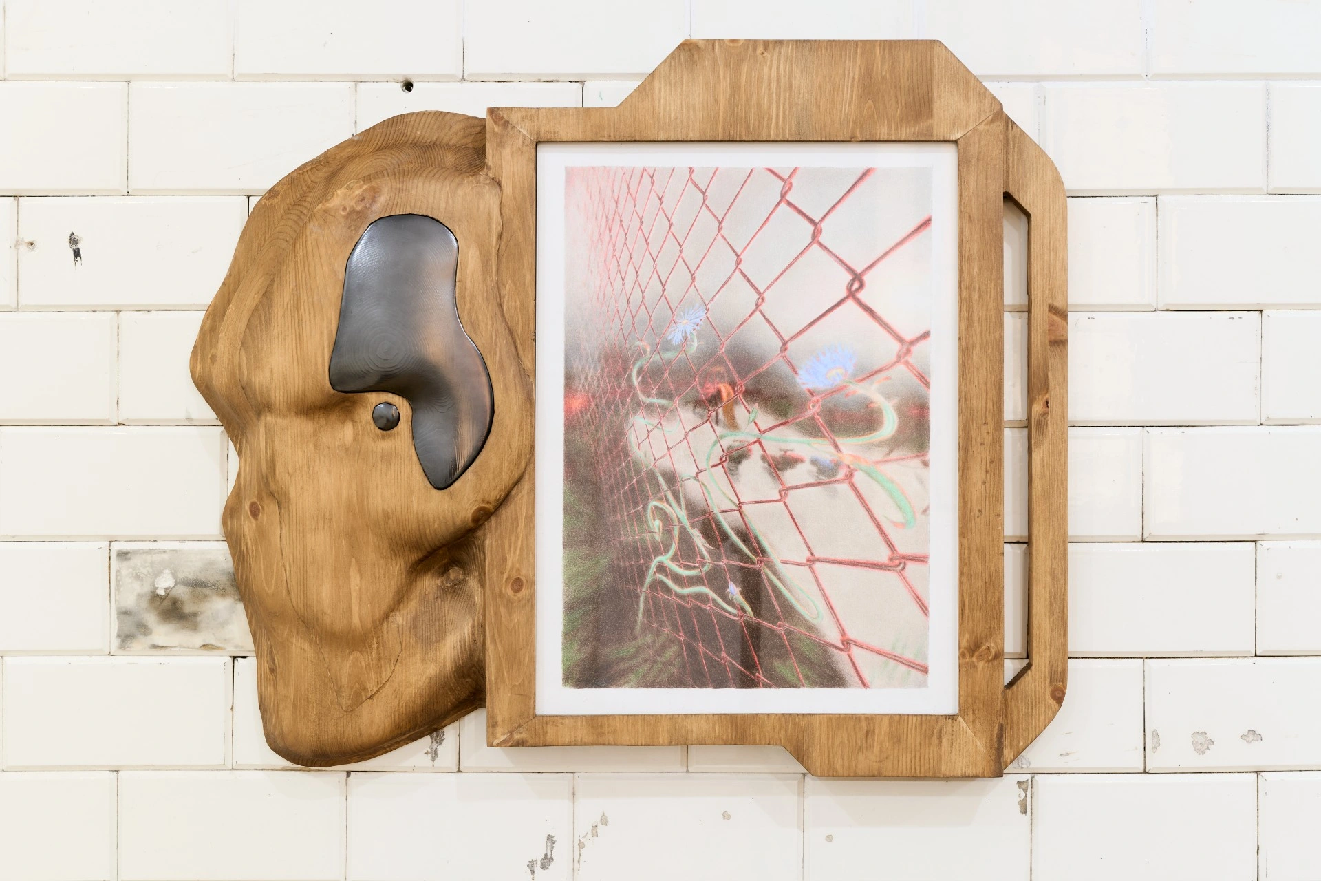 Tristan Gac, live-edge pine board with poured black metal blob and framed drawing of red chain-link fence tangled with blue flowers, white tile
