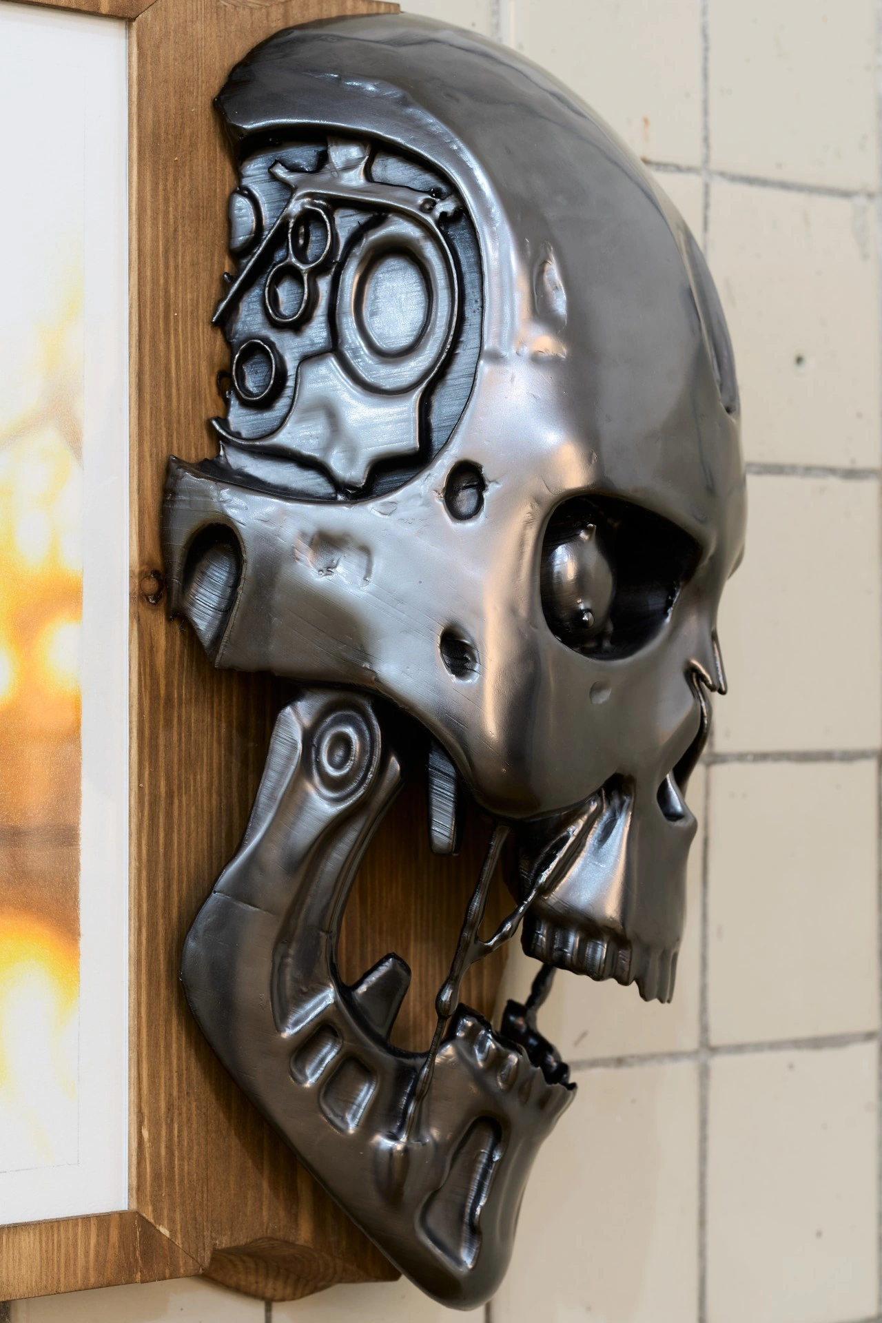 Tristan Gac, side detail of a mirror-black Terminator endoskull showing hydraulic jaw and machined cranium, mounted on pine over tile