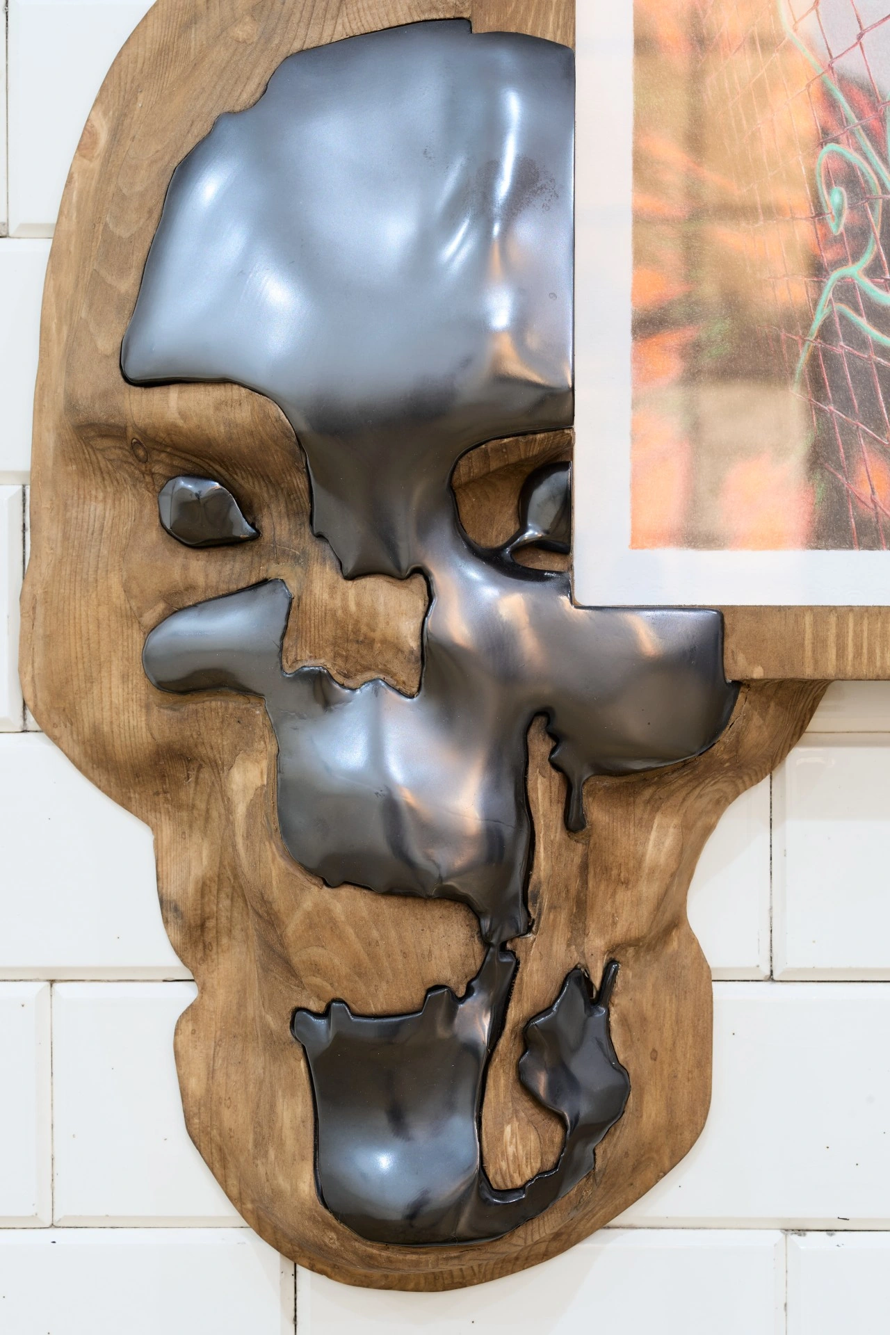 Tristan Gac, detail of a mirror-black half-skull emerging from carved pine beside a framed drawing of red mesh and fire