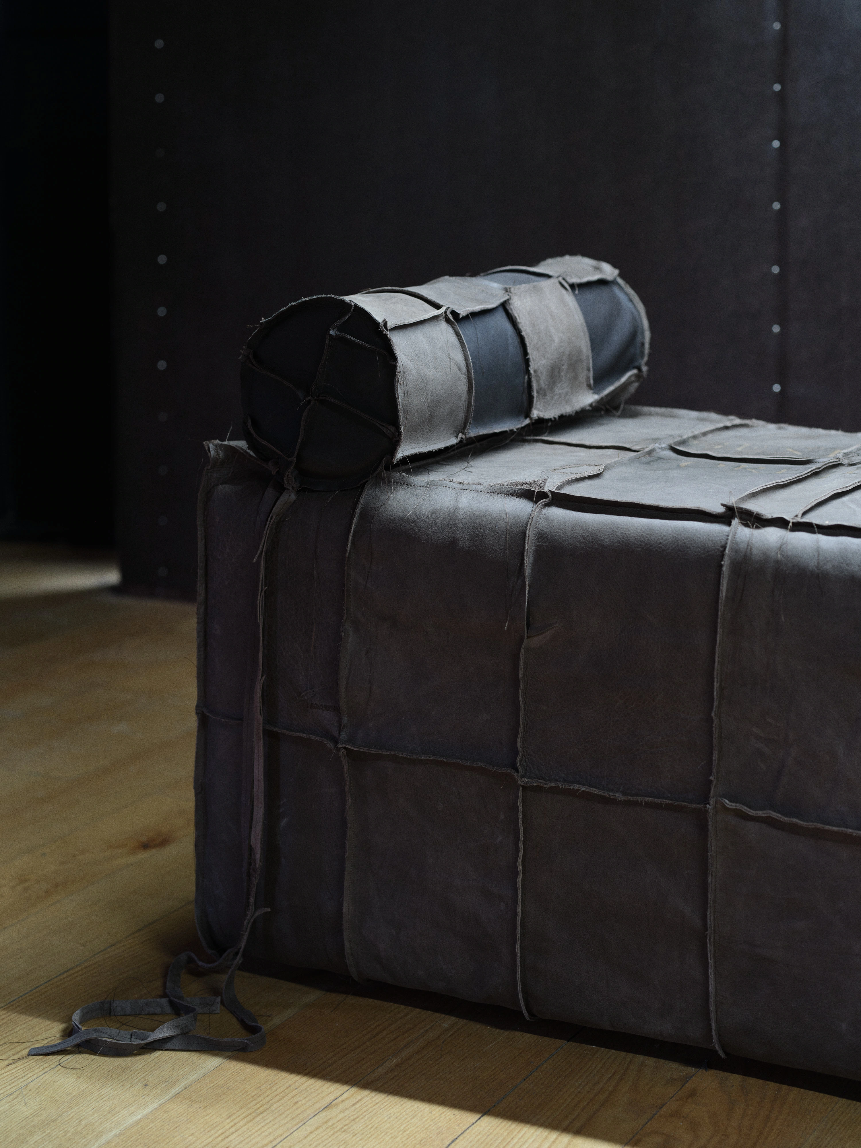 Jan Baszak, corner detail of a Catafalque showing raw outward seams between hide panels and a bolster banded in pale and black leather strips