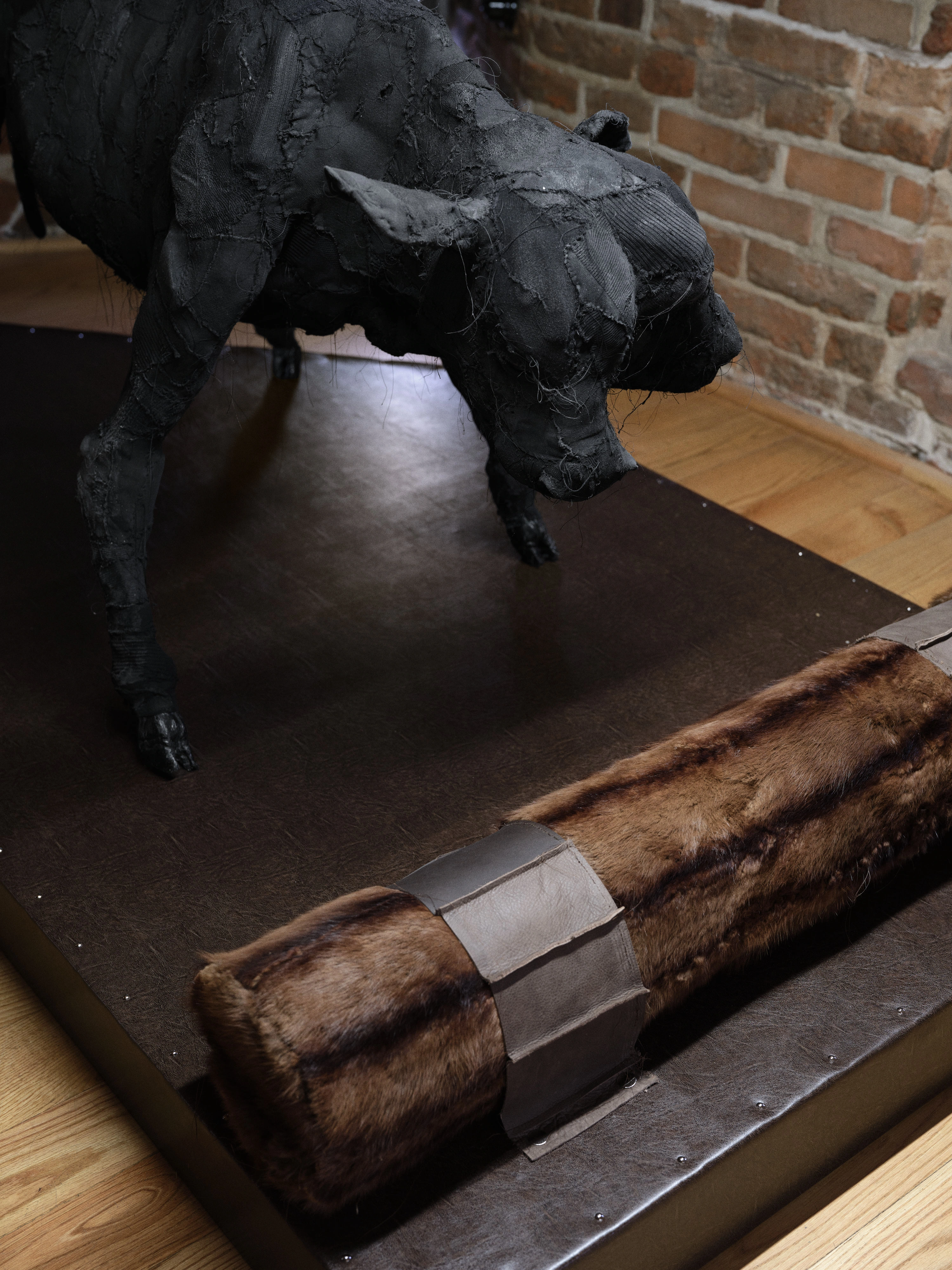Jan Baszak, detail of Two-Headed Calf with stitched black fabric limbs beside a rolled brown fur bolster banded with leather straps