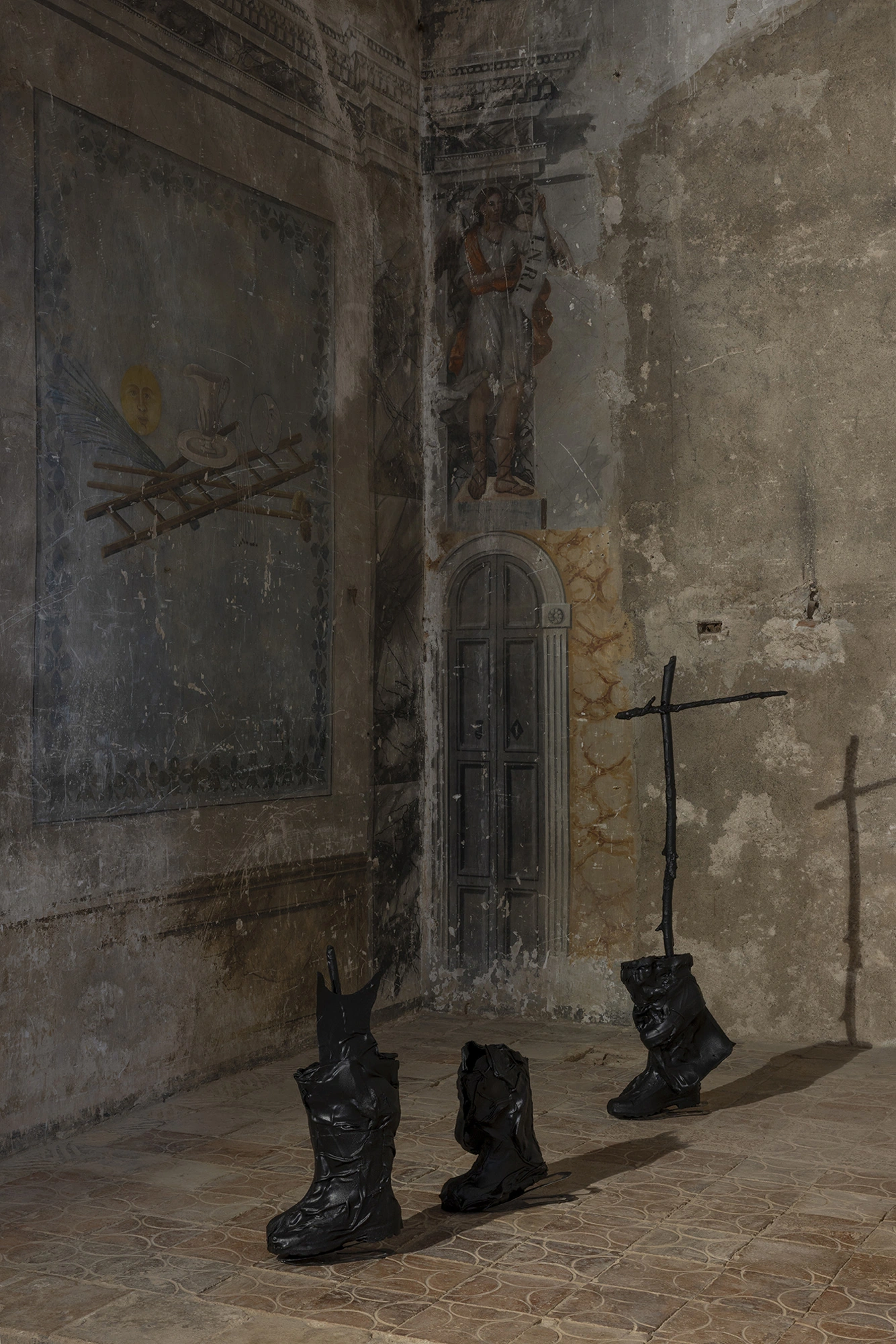 Sahatsa Jauregi's Pájaros: black rubber boots with cut-steel branches, set on a raised stone platform in a side chapel.