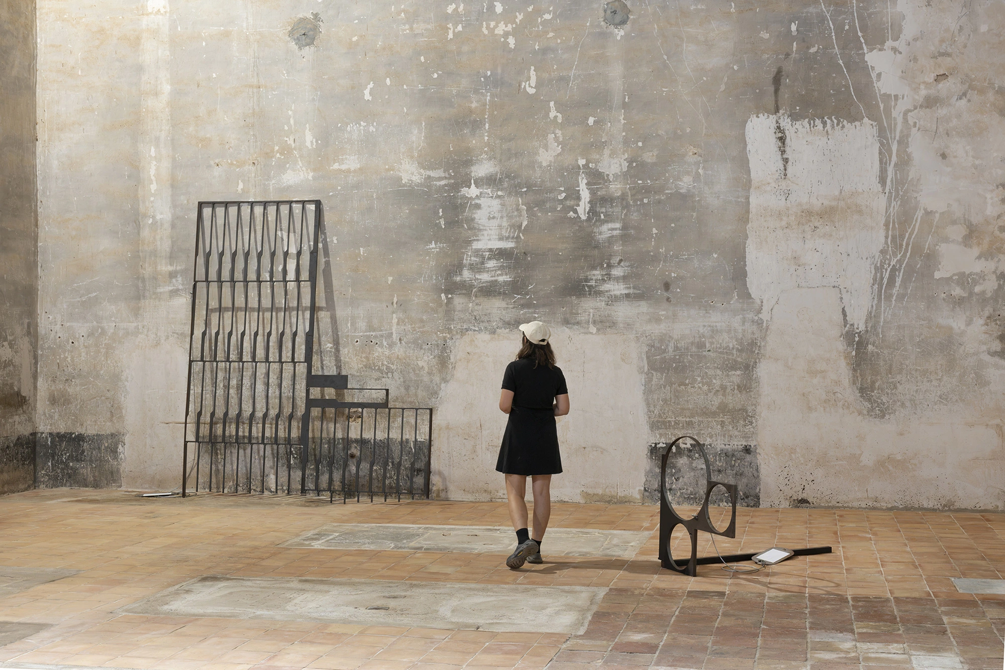 A visitor in the nave of the Church of Sant Feliu, Lladó, standing between two steel works by Jordi Mitjà.