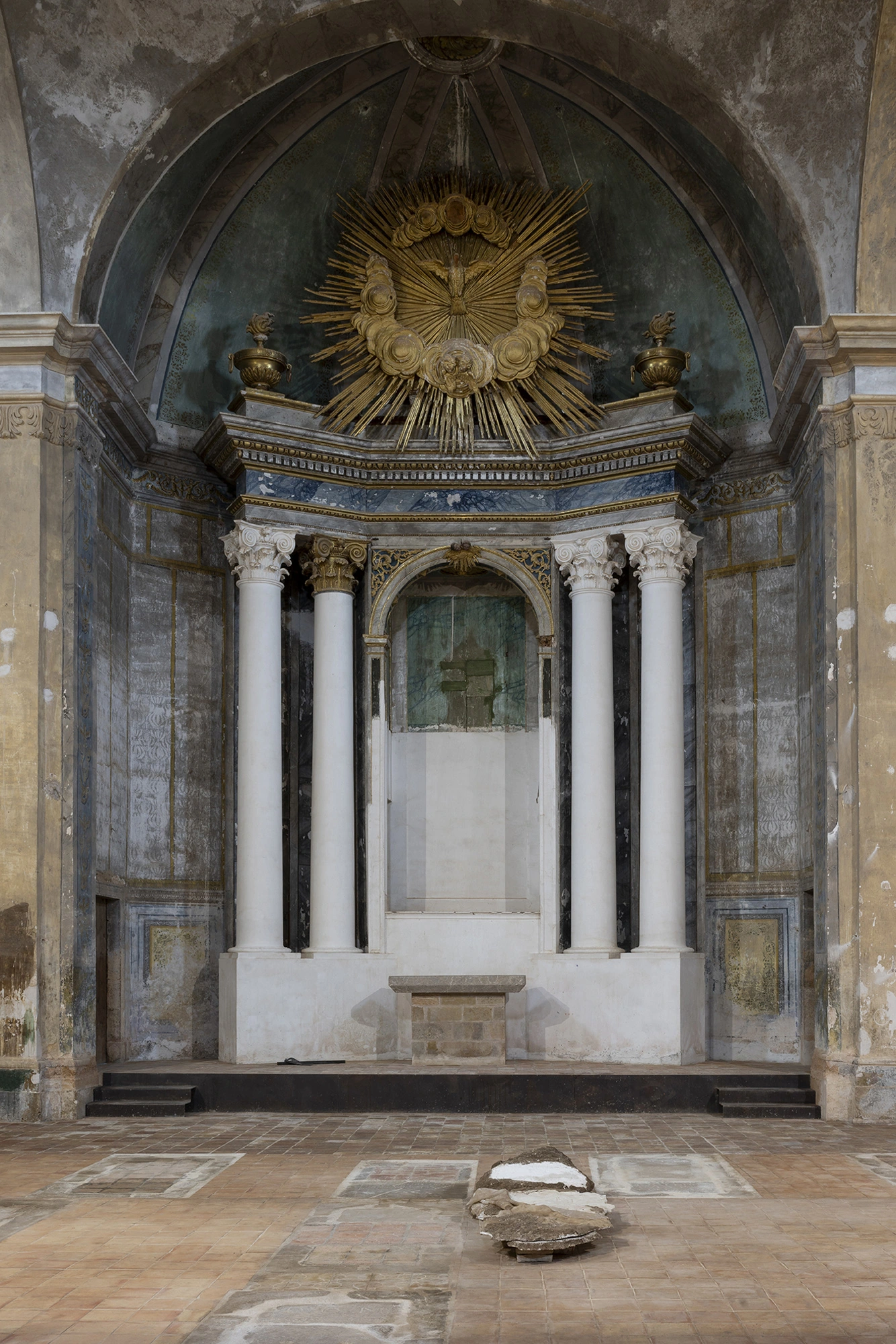 The apse of the Church of Sant Feliu, Lladó, its gilded sunburst and dove above a stripped altar, with a work from Monia Ben Hamouda's Ghost series on the floor.