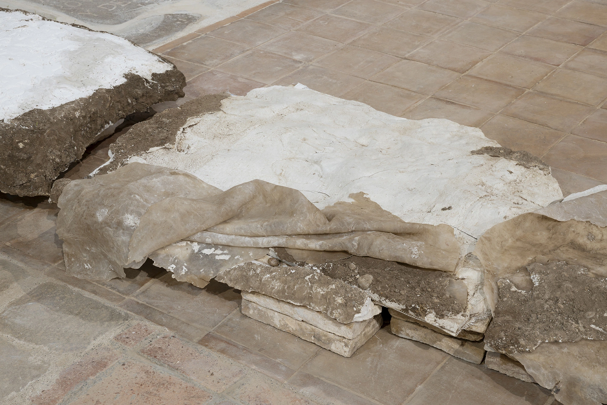 A sheet of honey-coloured silicone peeled from a grave slab and folded over the plaster cast beneath it, propped on oak battens.