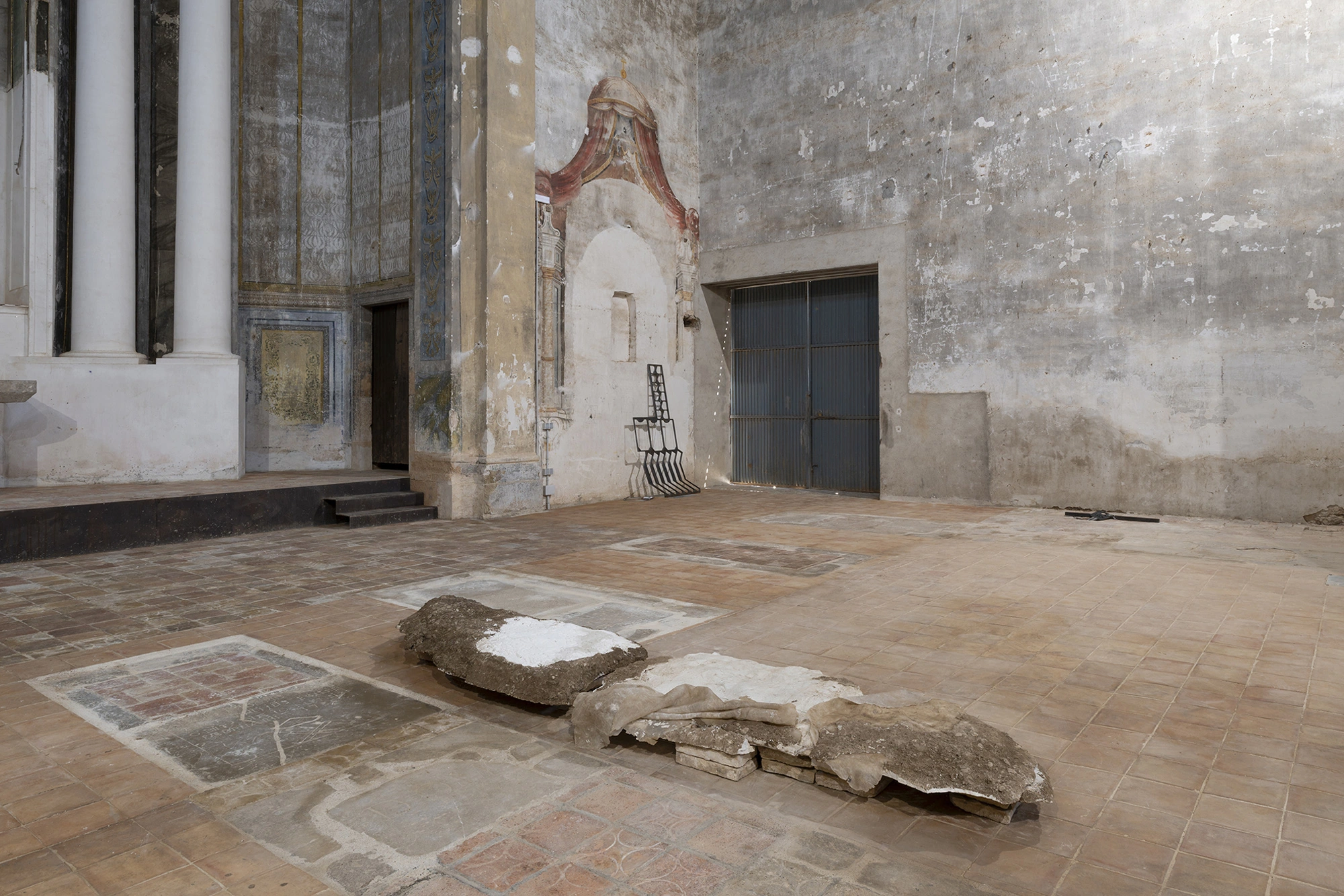 Installation view of KIN TOO in the Church of Sant Feliu, Lladó, with a Ghost work on the floor and a steel piece by Jordi Mitjà beyond.