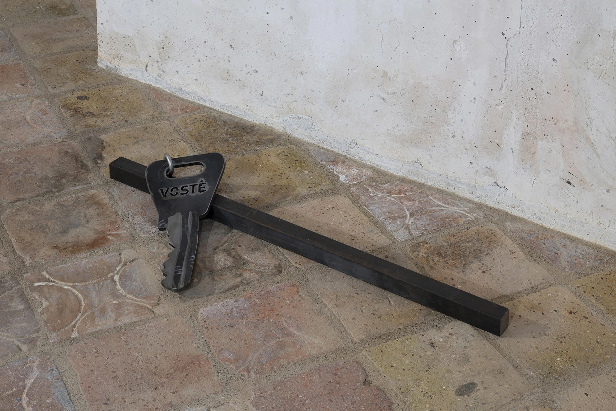 Jordi Mitjà's Clau Doblegada per a vostè, an enlarged iron and stainless steel key, crossing an iron bar.