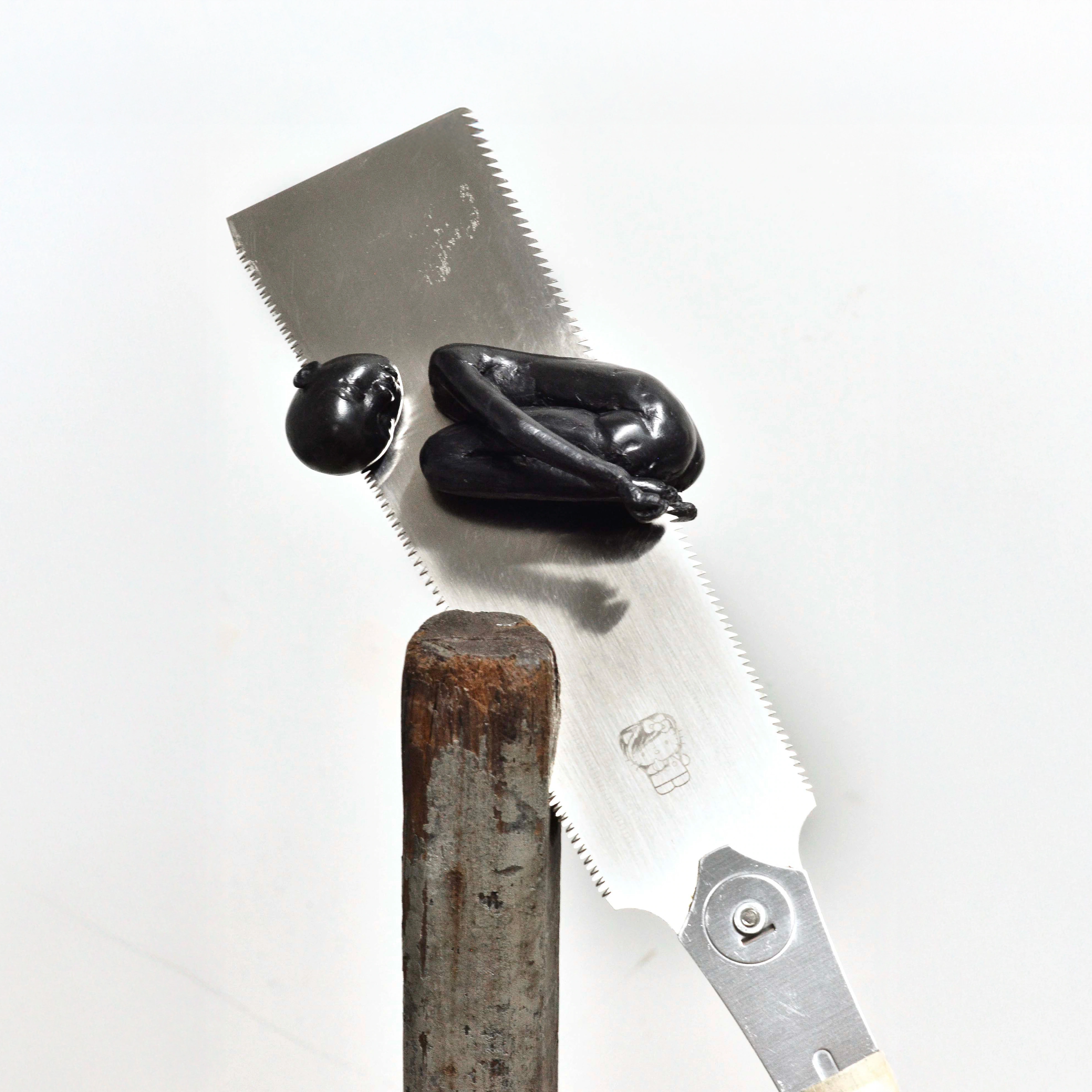 Alicia Bilbao, Executioner, 2026, detail of the figure on the saw. Epoxy clay, nokogiri saw, wood