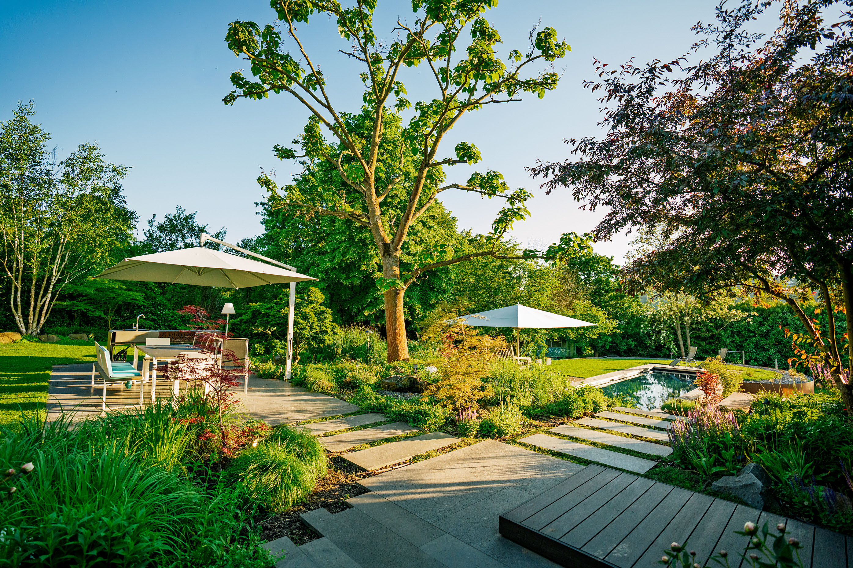 Moderner Familiengarten mit naturnaher Bepflanzung und Elementen aus Cortenstahl 
