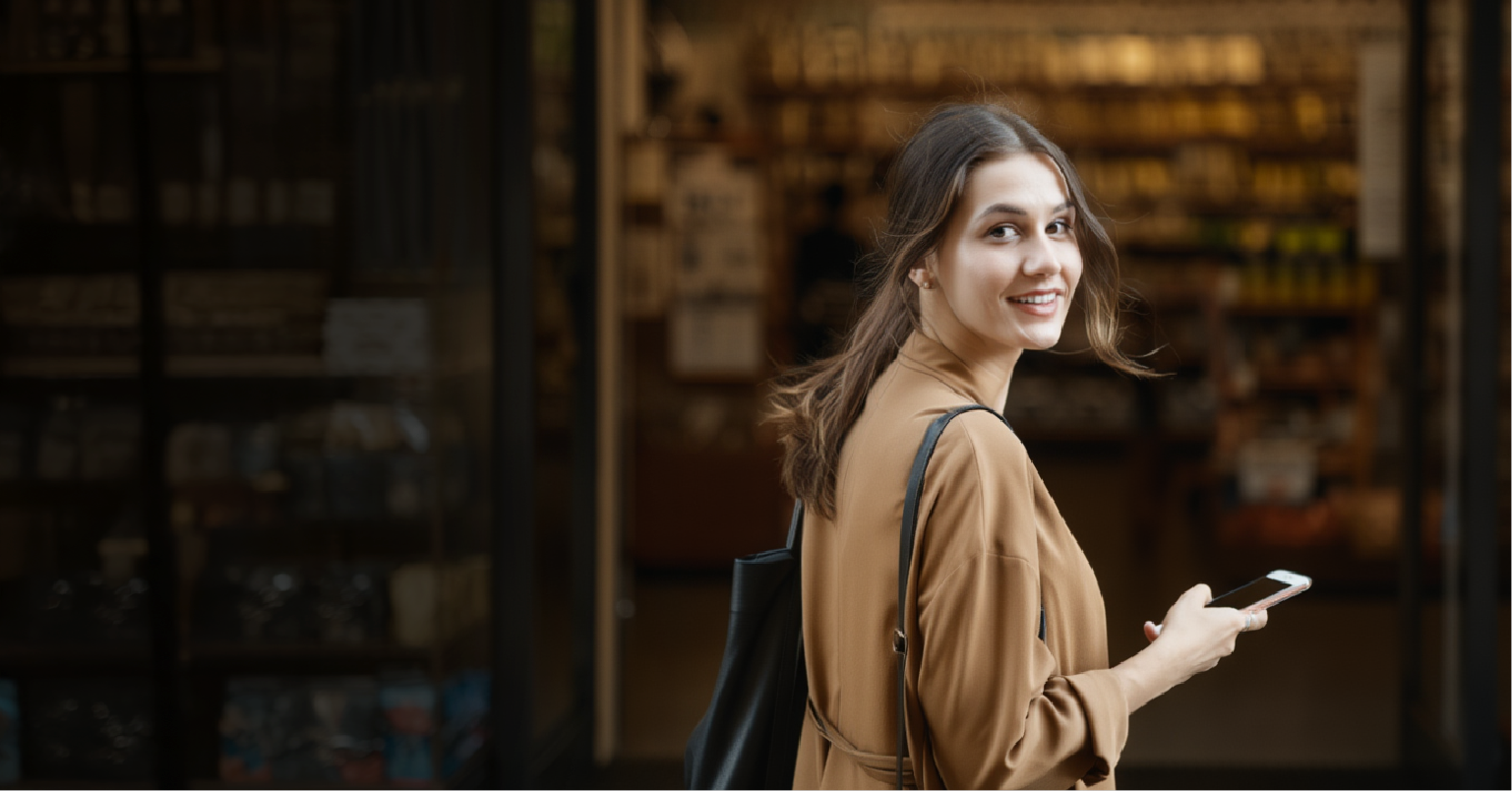 Woman walking into store holding mobile phone
