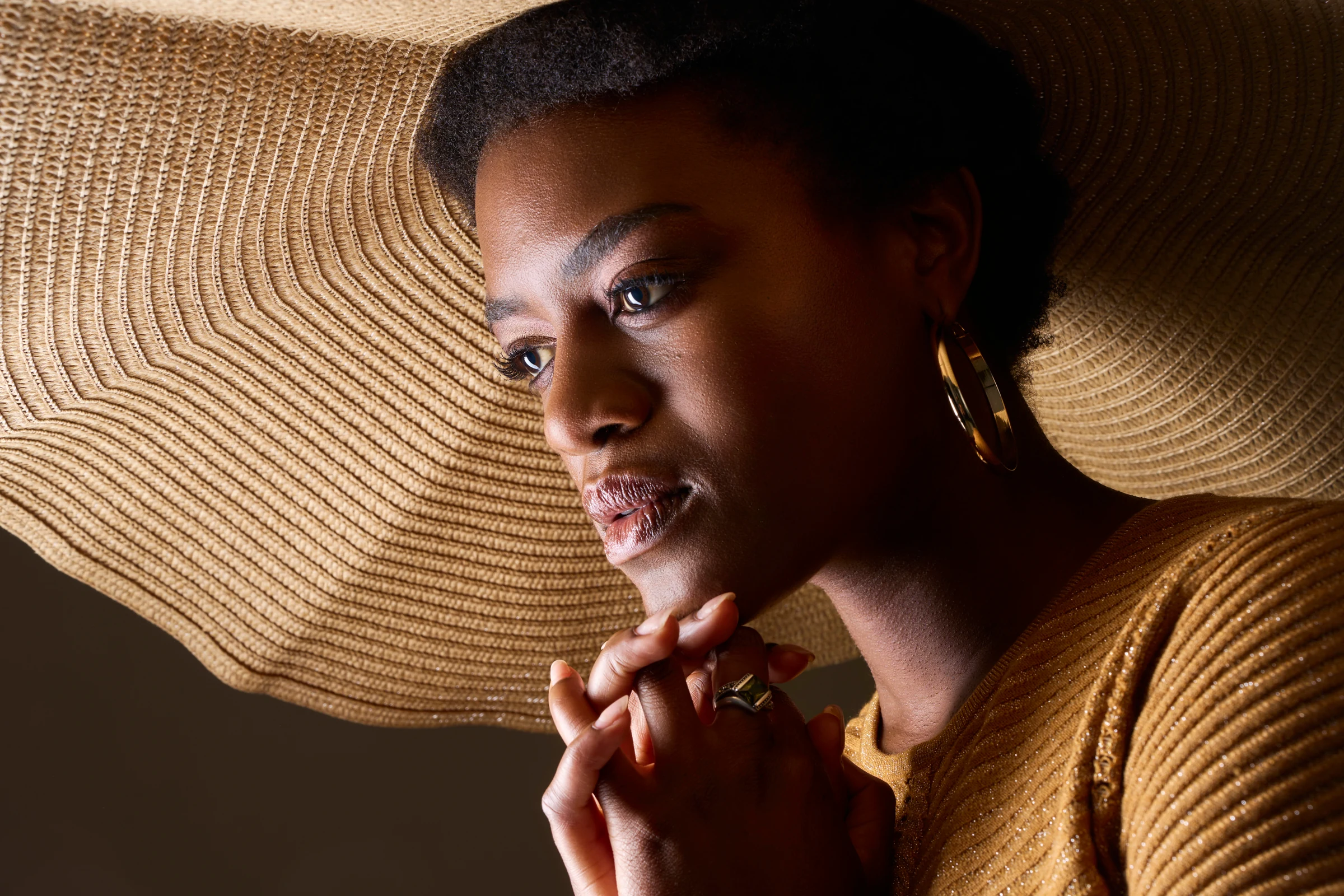 Portrait éditorial d’une femme éclairée par l’ombre graphique d’un chapeau. Photographie réalisée par Frédéric Sicard au studio de Morières-lès-Avignon.