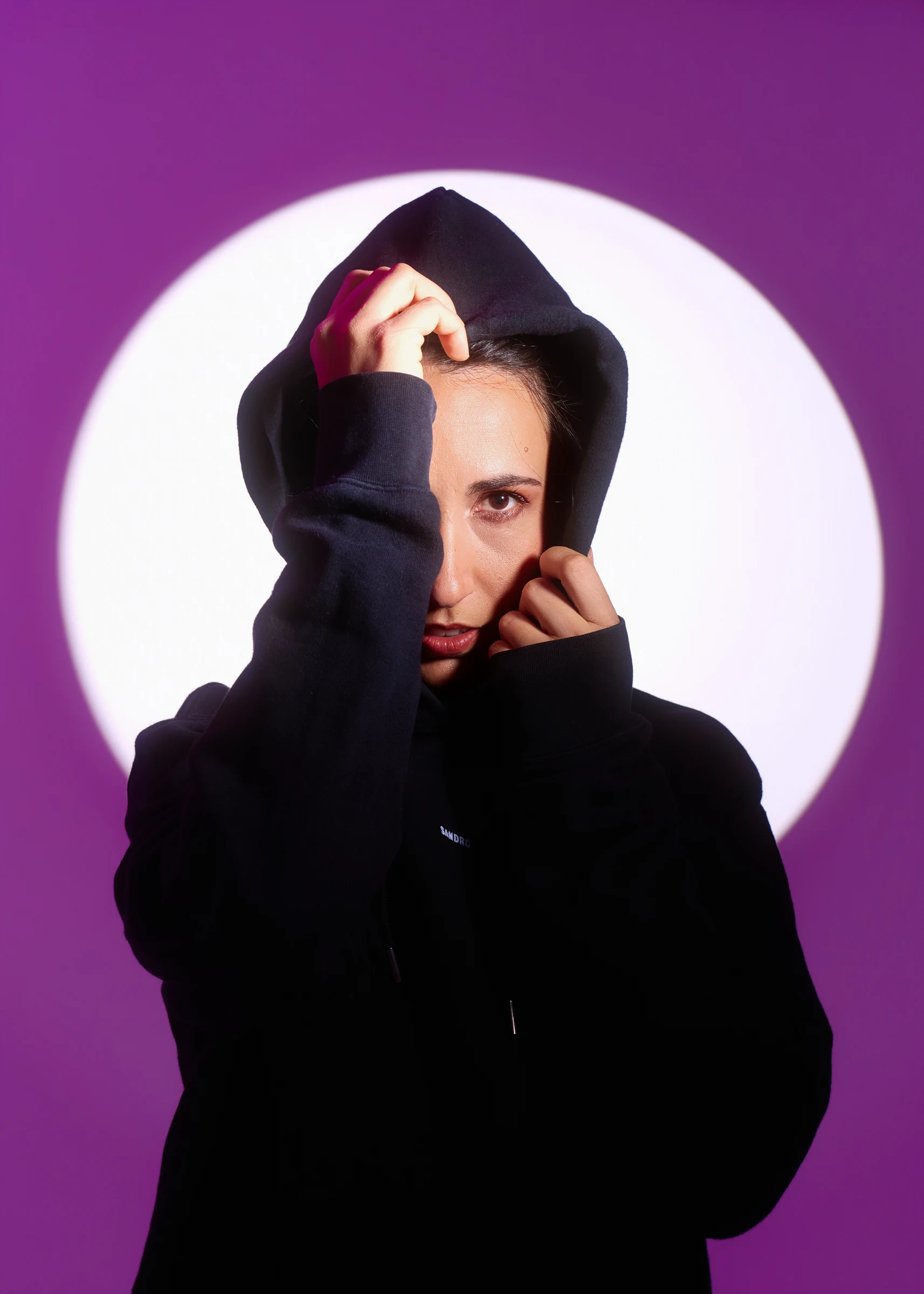Portrait éditorial d’une personne vêtue de noir devant un cercle violet. Photographie réalisée par Frédéric Sicard au studio de Morières-lès-Avignon.