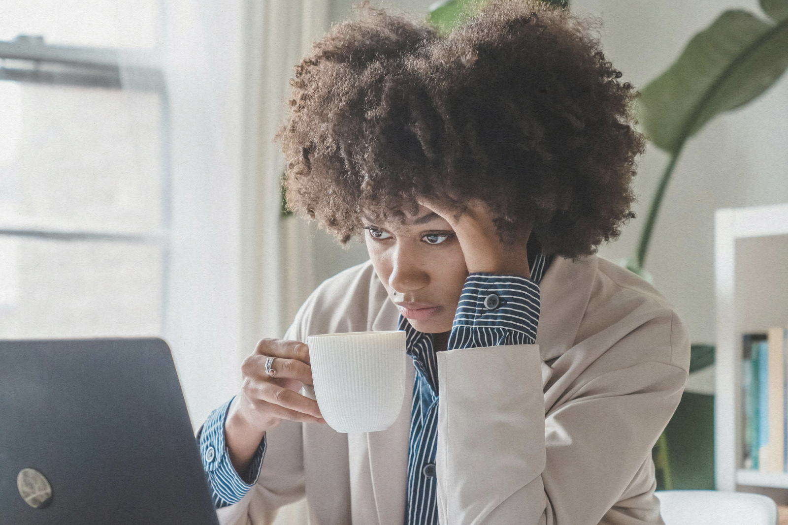 woman sitting at desk with laptop and coffee