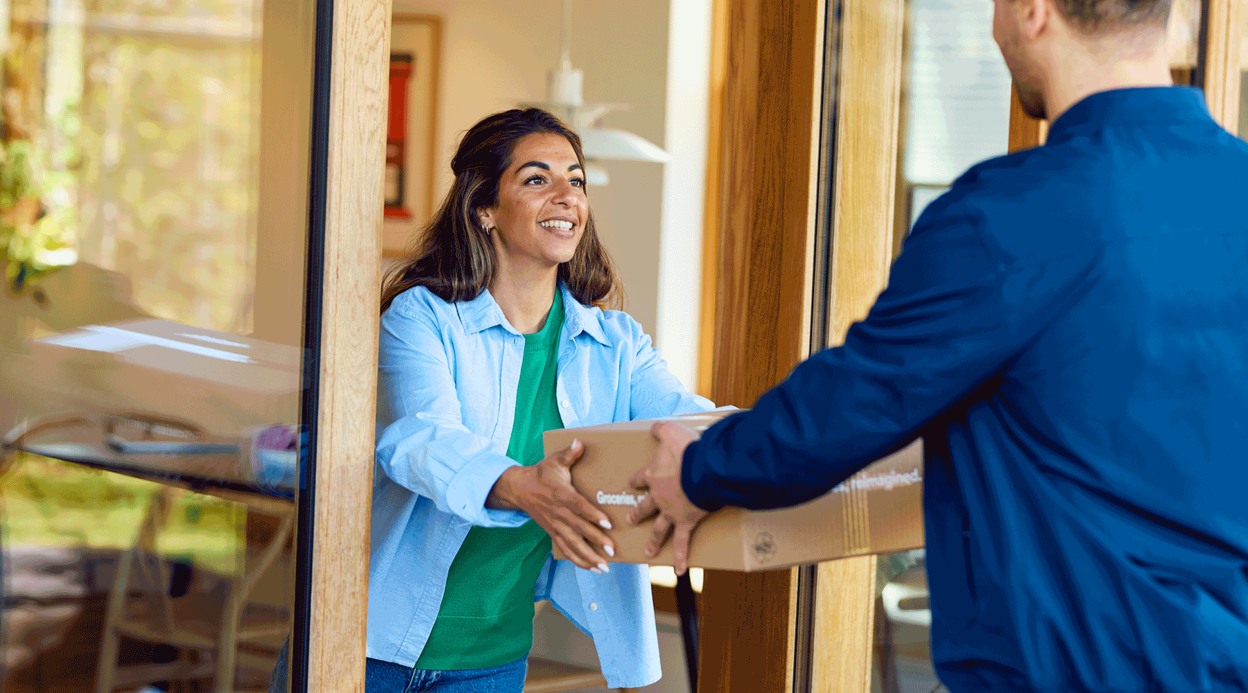 Woman receiving package from delivery man. Image.