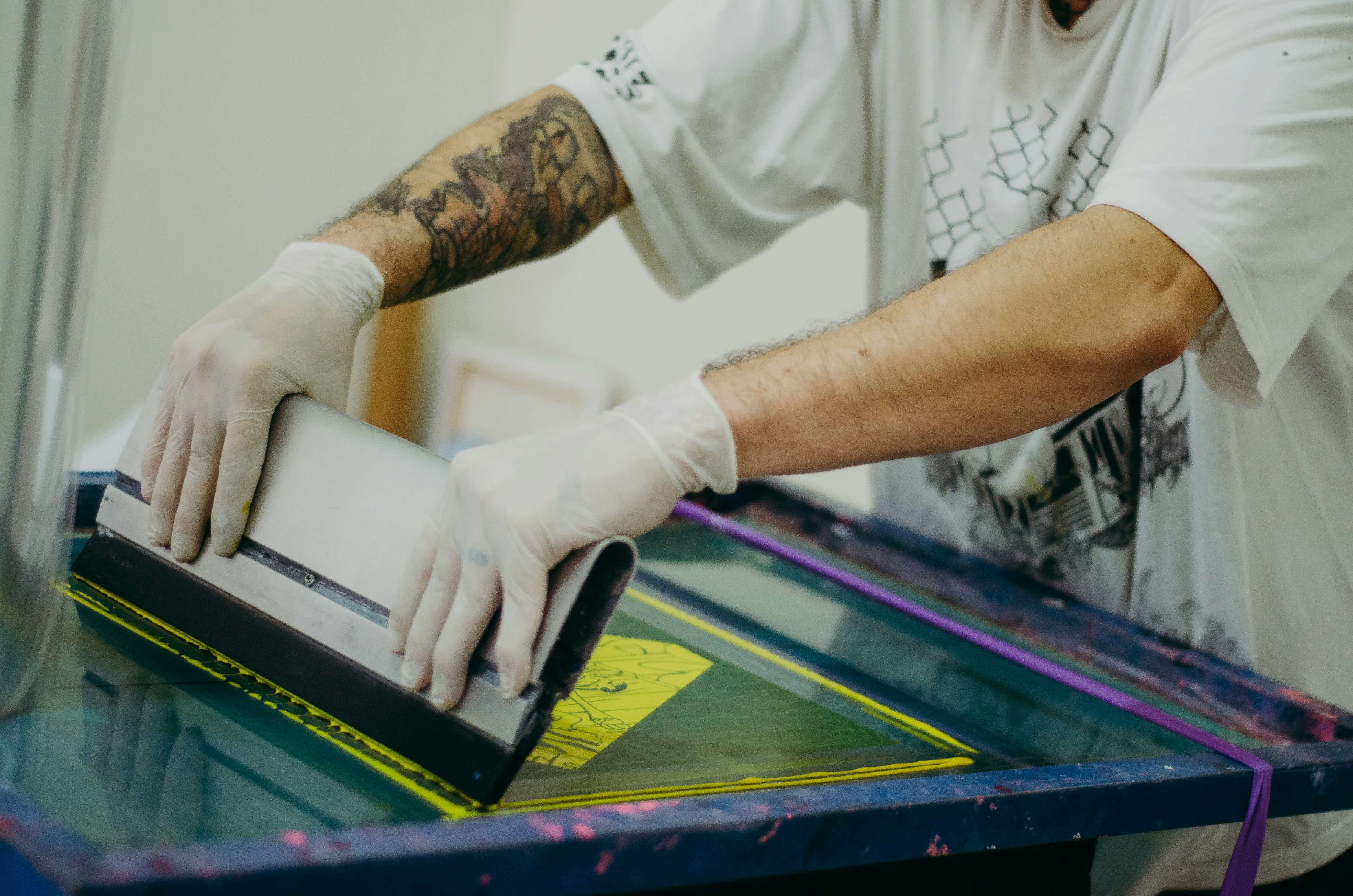 Raclette étalant de l'encre sur un t-shirt en sérigraphie