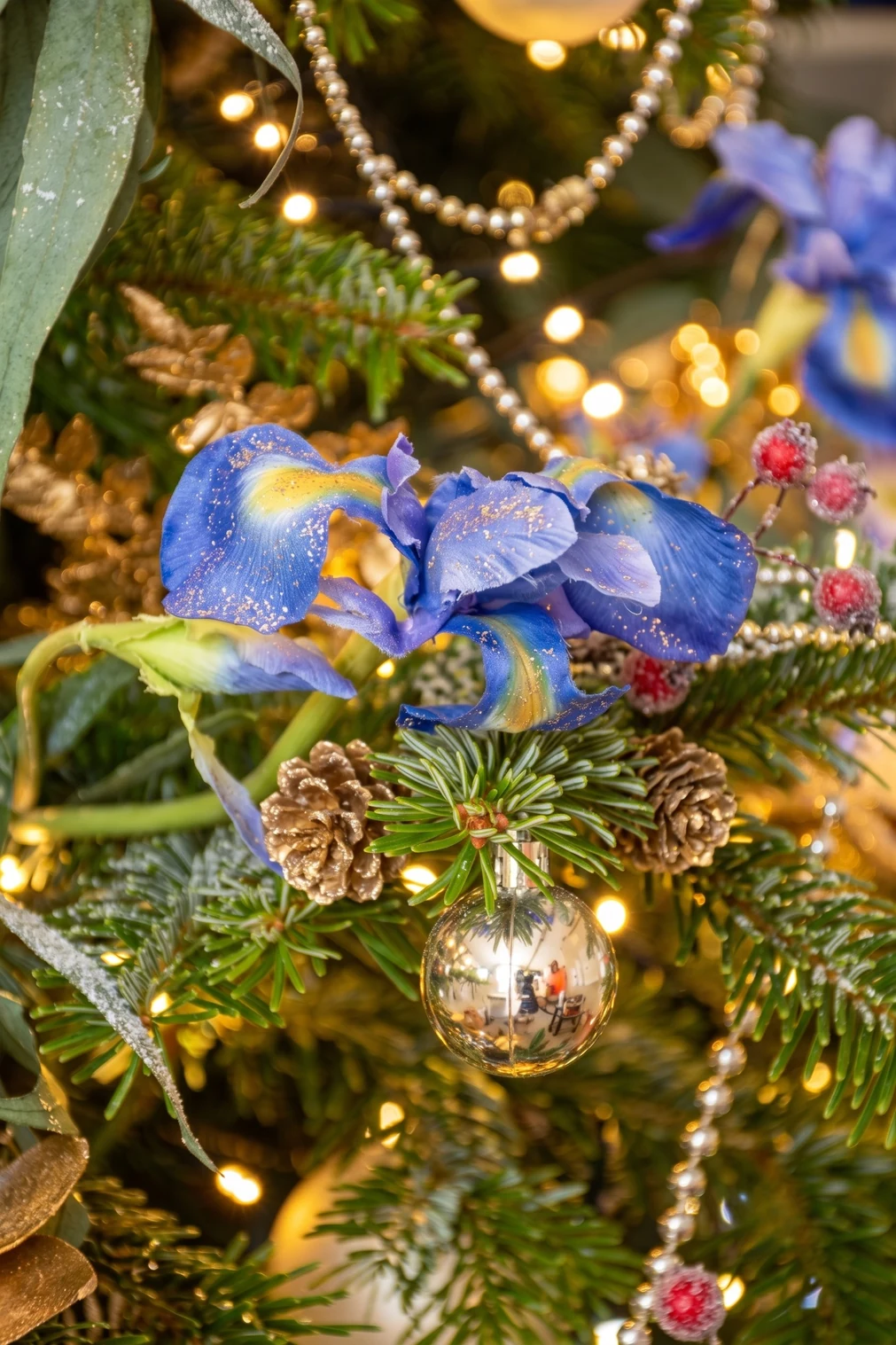 Détail d'un sapin de Noël : iris bleu, pommes de pin et boule argentée