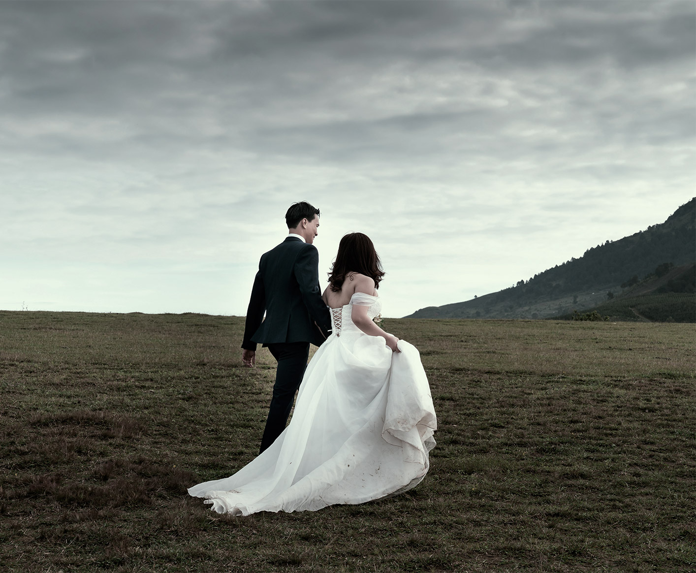 The bride and groom walking in a field.