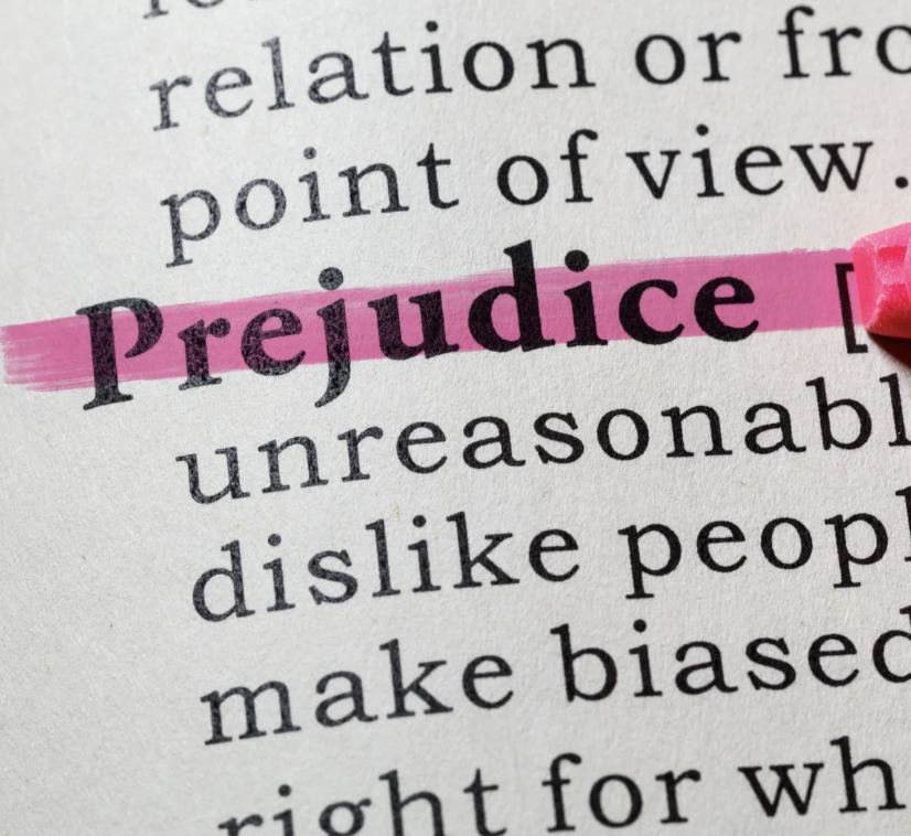 Das Wort ‚Prejudice‘ in einem Wörterbuch wird mit einem pinken Textmarker hervorgehoben – Symbol für unbewusste Vorurteile (Unconscious Bias) und die Bedeutung von Bewusstseinsbildung in eLearning-Trainings.