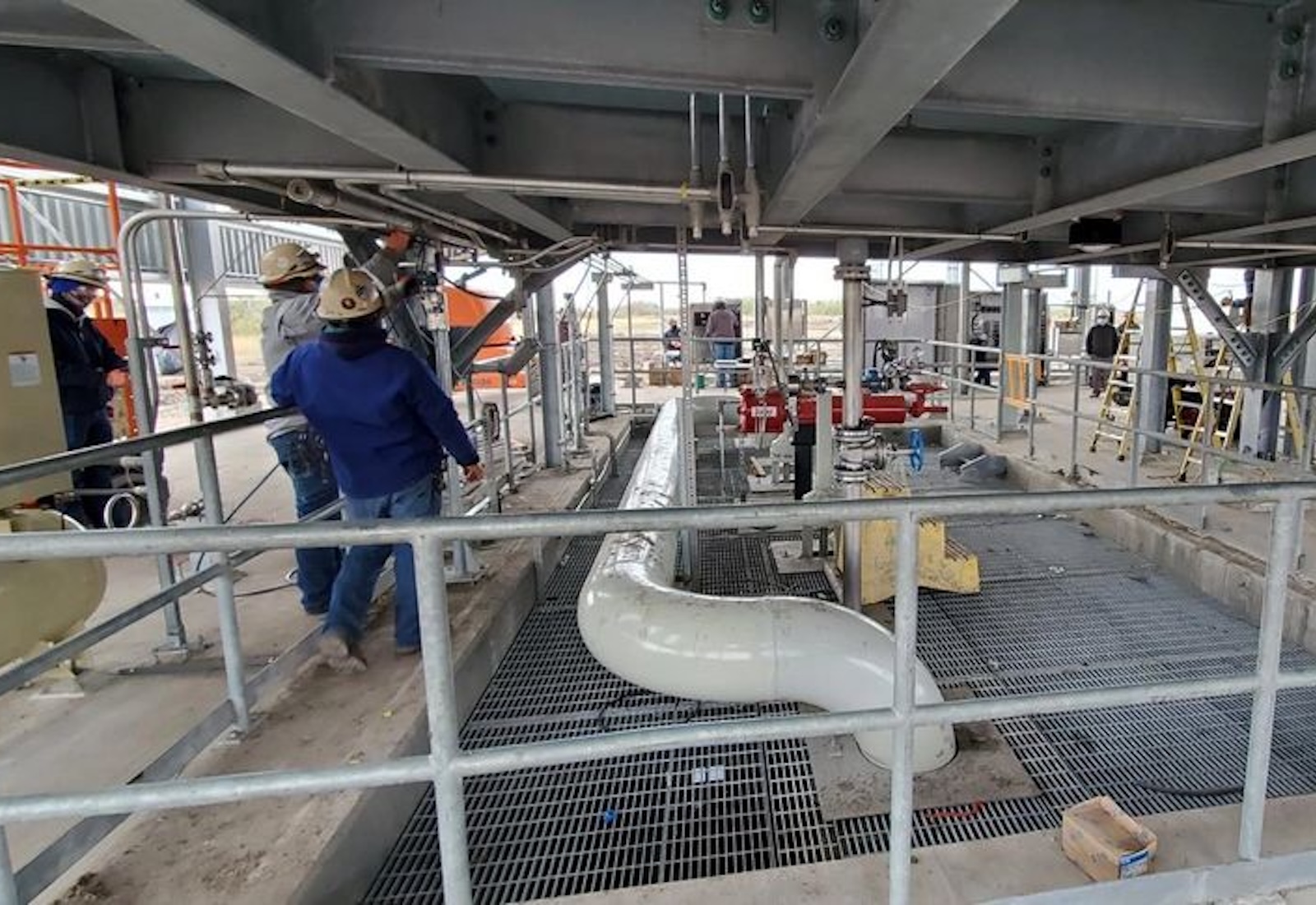 Workers around a pipe leading into the ground