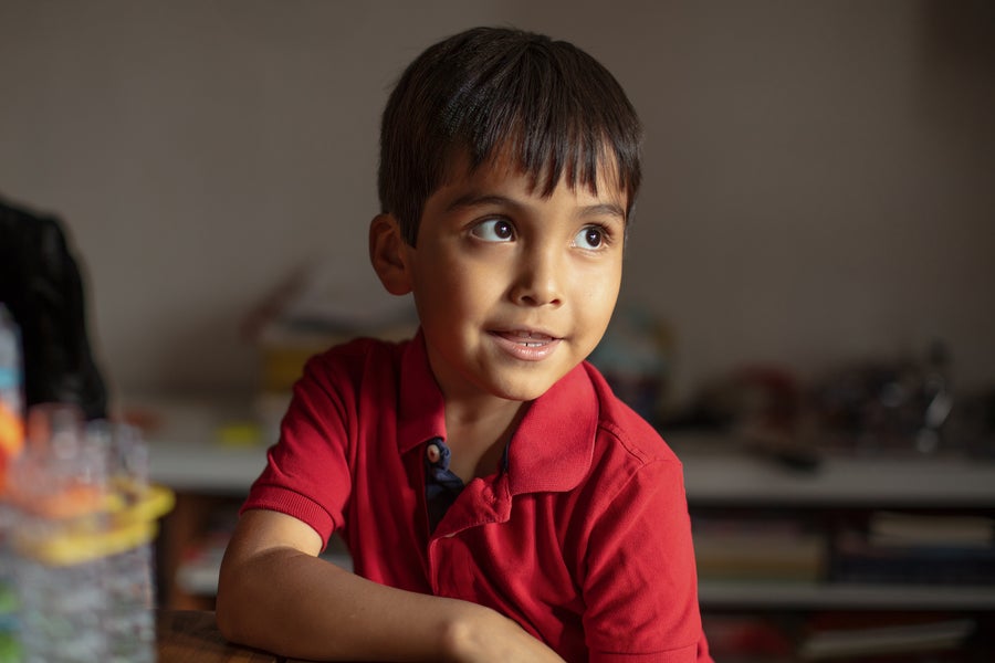 Young boy in red shirt smiling at table