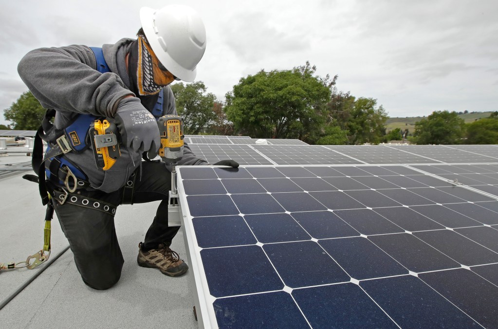A worker installs solar panels in Hayward on April 29, 2020. AP Photo/Ben Margot