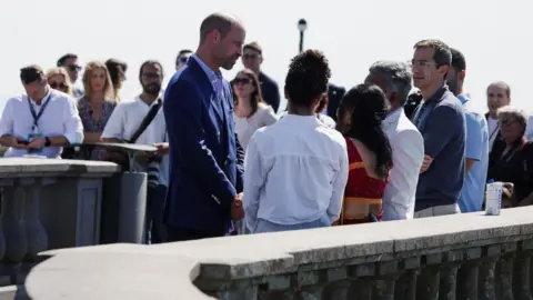 Reuters William talking to finalists. A short distance away is a small crowd of people watching