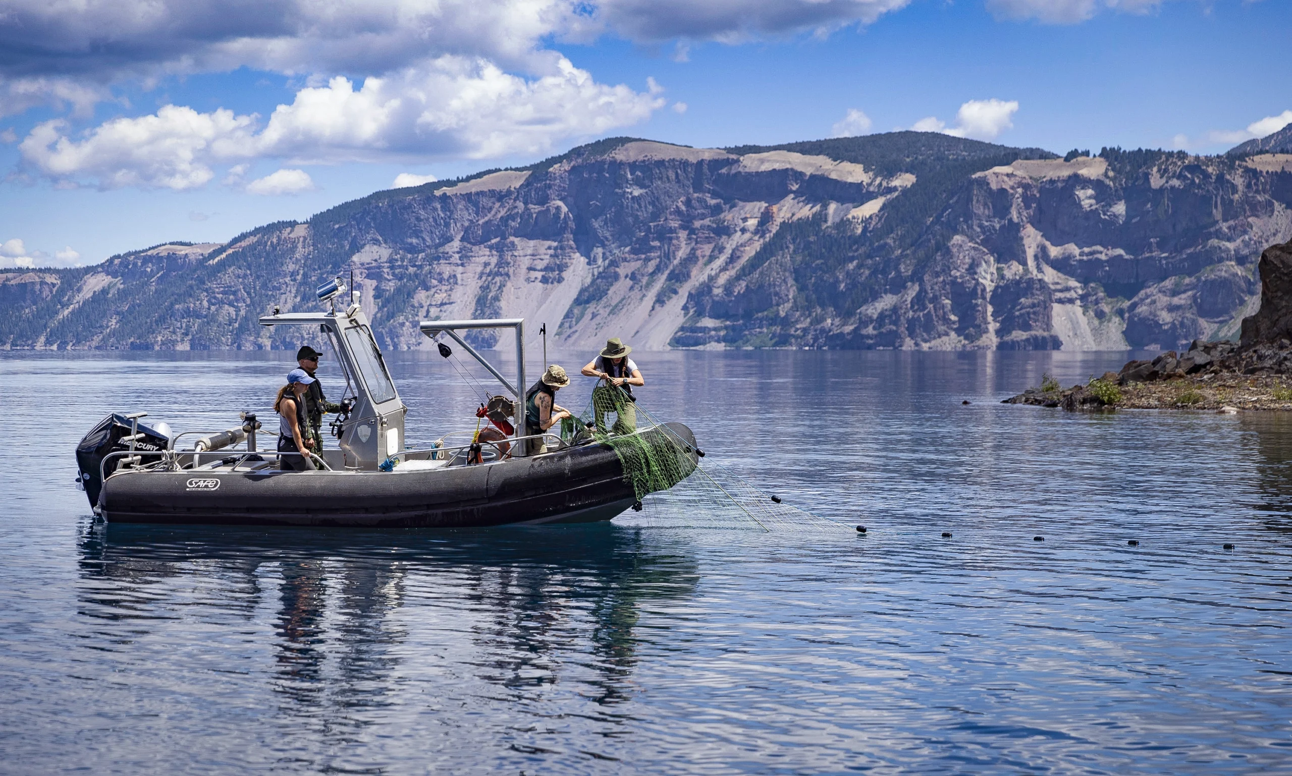 A boat drags a gill net on Crater Lake’s glassy surface.