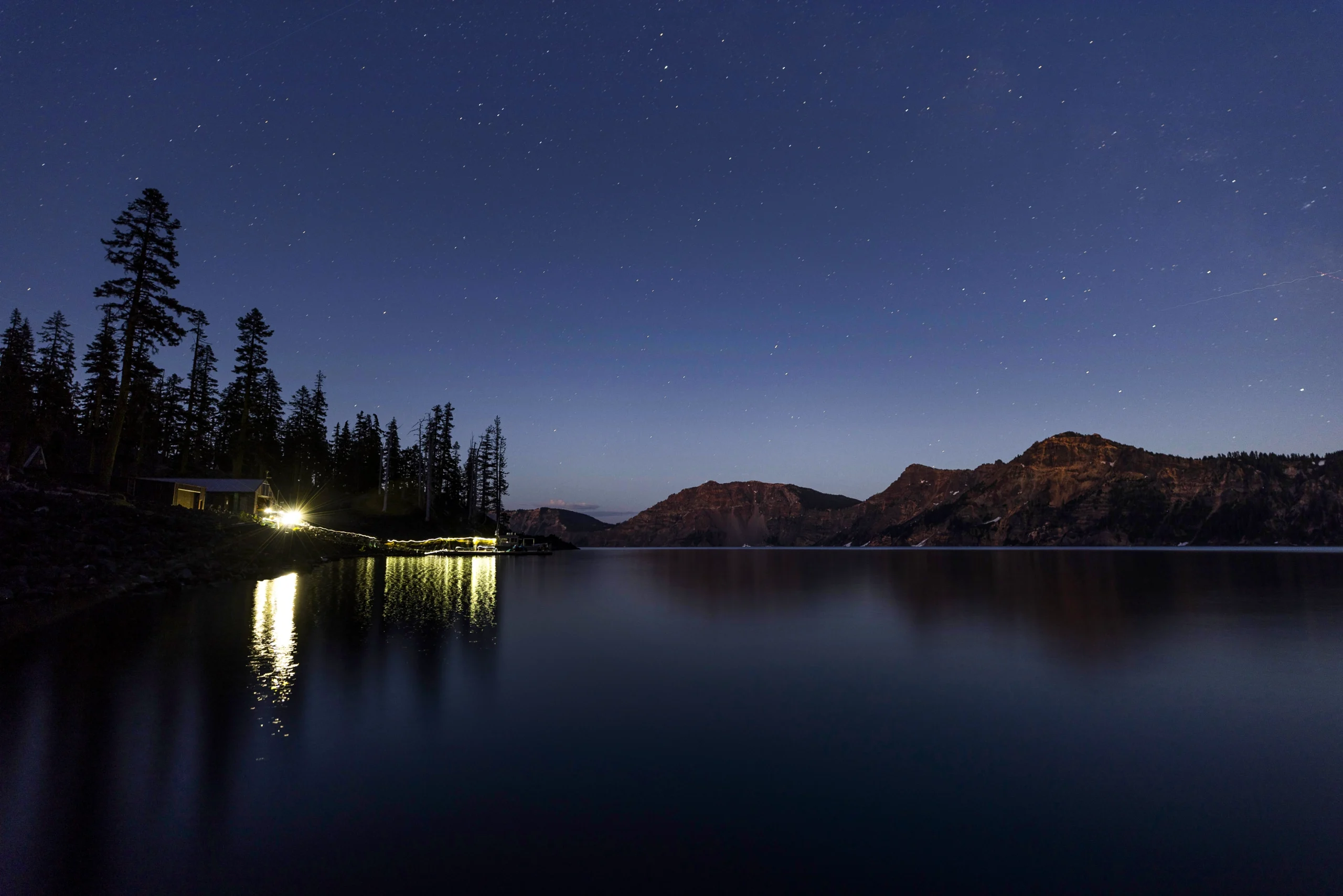 A photo of the lake at night, with the field station illuminated by its artificial light.