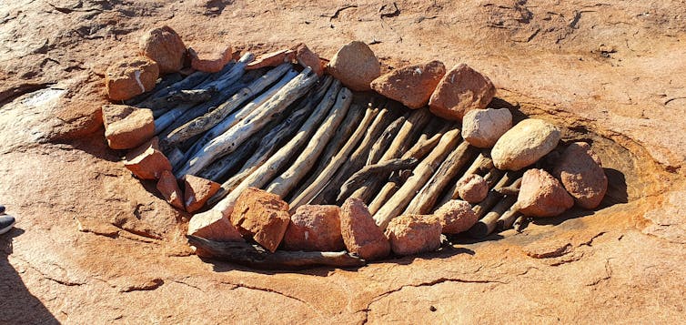 A granite rock-hole has been managed using traditional practices. Small stones are placed around the perimeter and logs have been laid across the top.